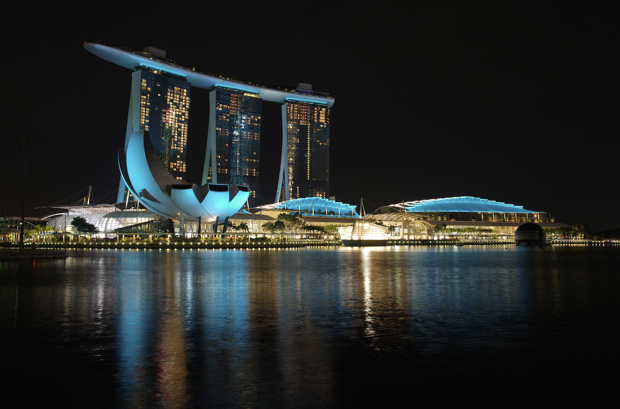 Marina Bay Sands and ArtScience Museum, Singapore at night, reflected in water.