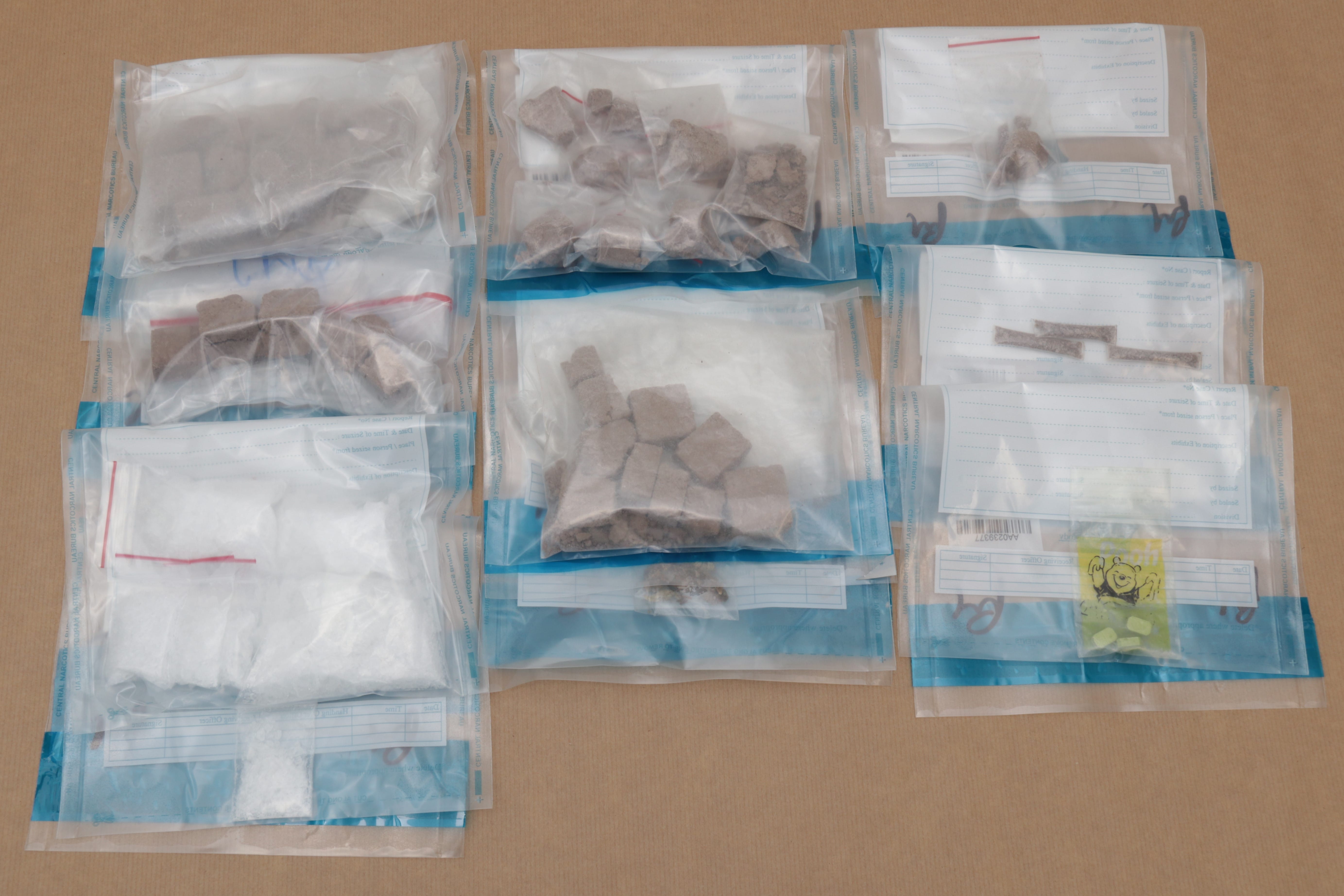 Bags with possible narcotics: cube-shaped brown substances, white powder, pills, and Winnie the Pooh sticker.