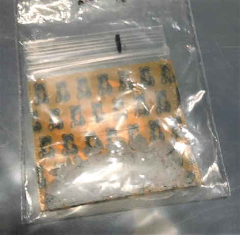 Clear plastic bag containing paper sheet with cartoon bears and white crystal-like substance.