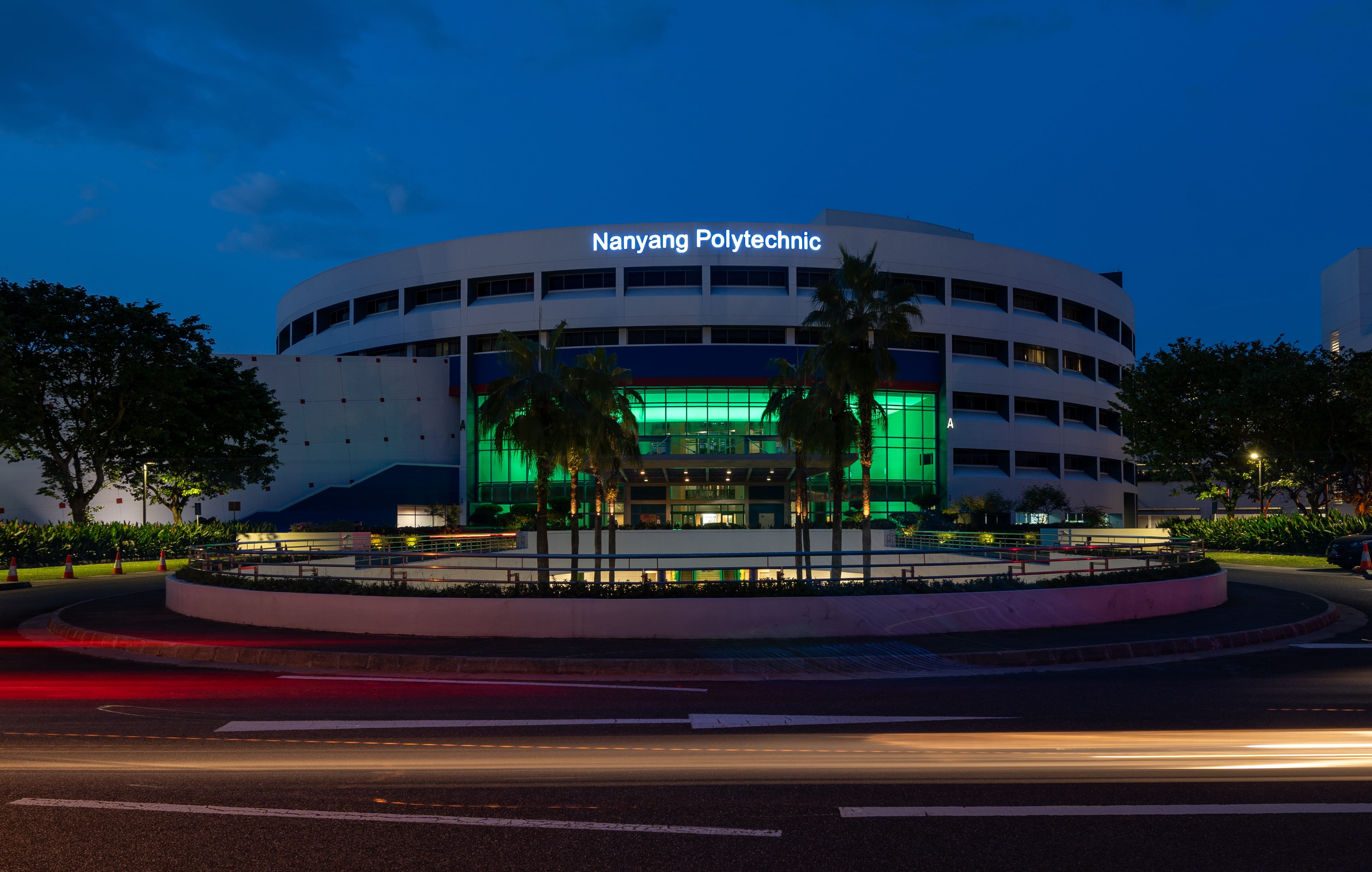 Night view of Nanyang Polytechnic building with long exposure car light trails.