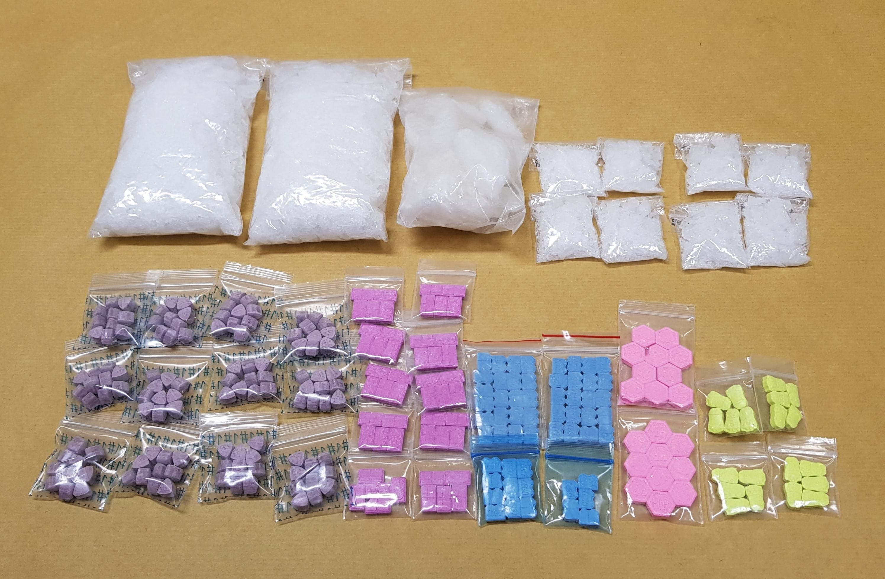 Assorted small bags and clear bags containing colorful pills and a white crystalline substance.