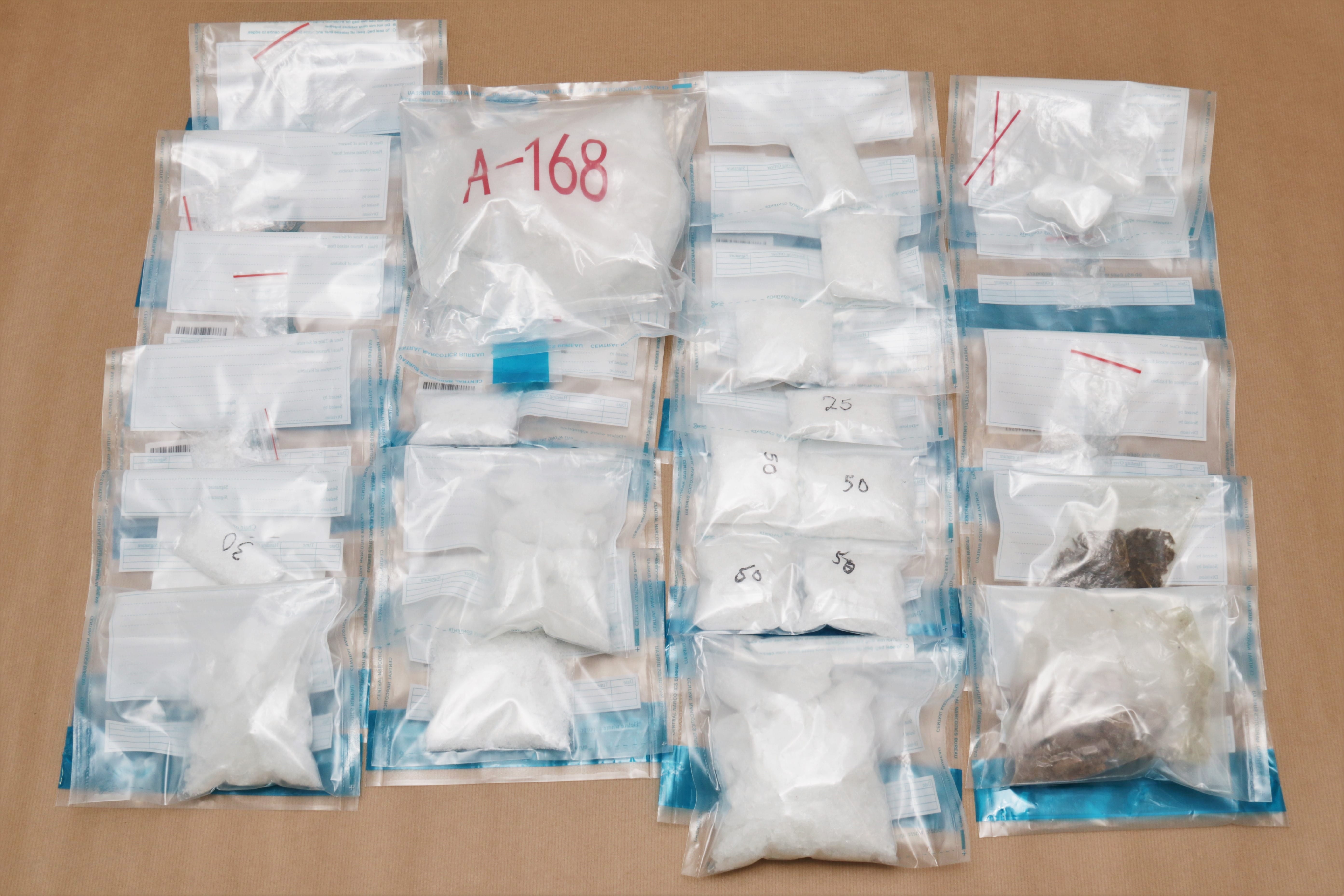 Multiple clear bags filled with white/brown substances, some labeled with numbers, on a brown surface.