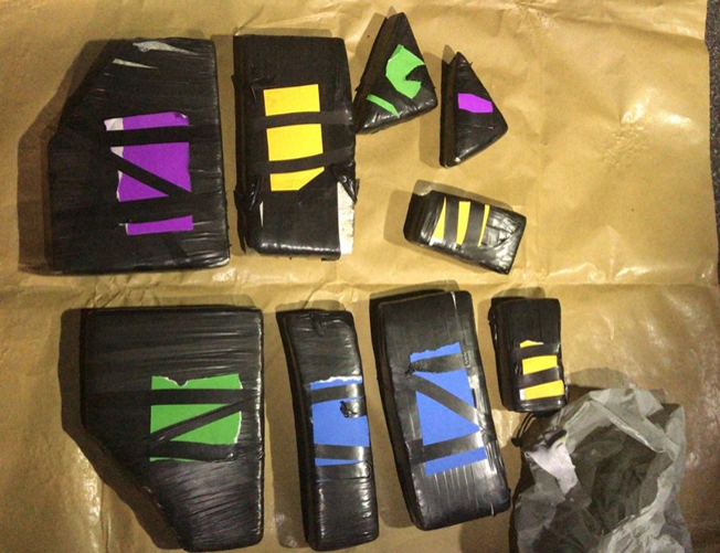 Multiple black wrapped packages with colored tape on brown paper.