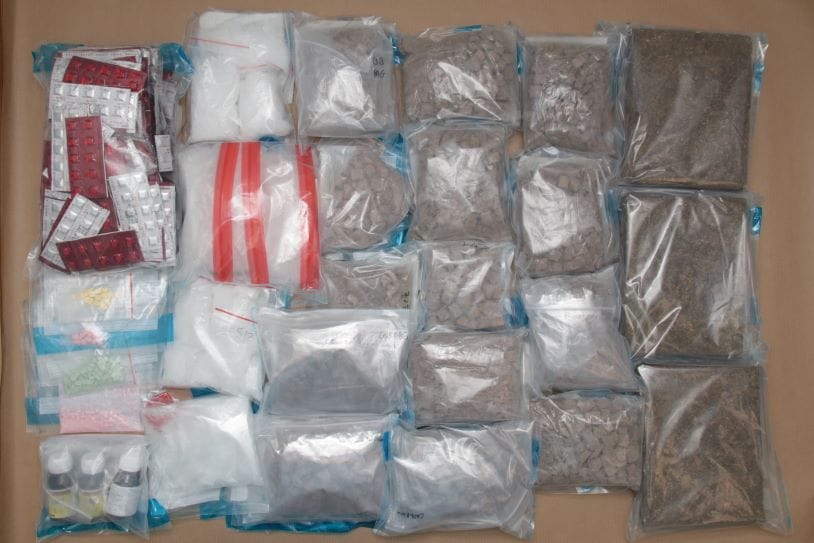 Variety of pills, powders, and substances in plastic bags on a flat surface.