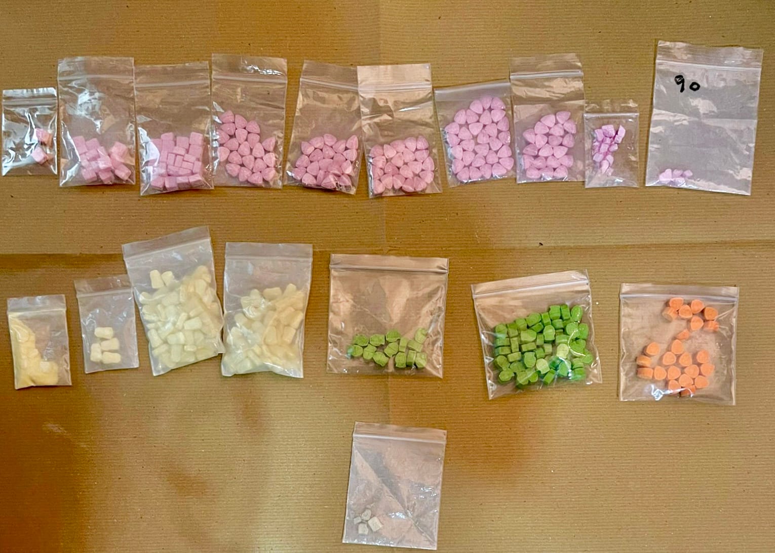Clear plastic bags with assorted colored candies in rows on a surface.