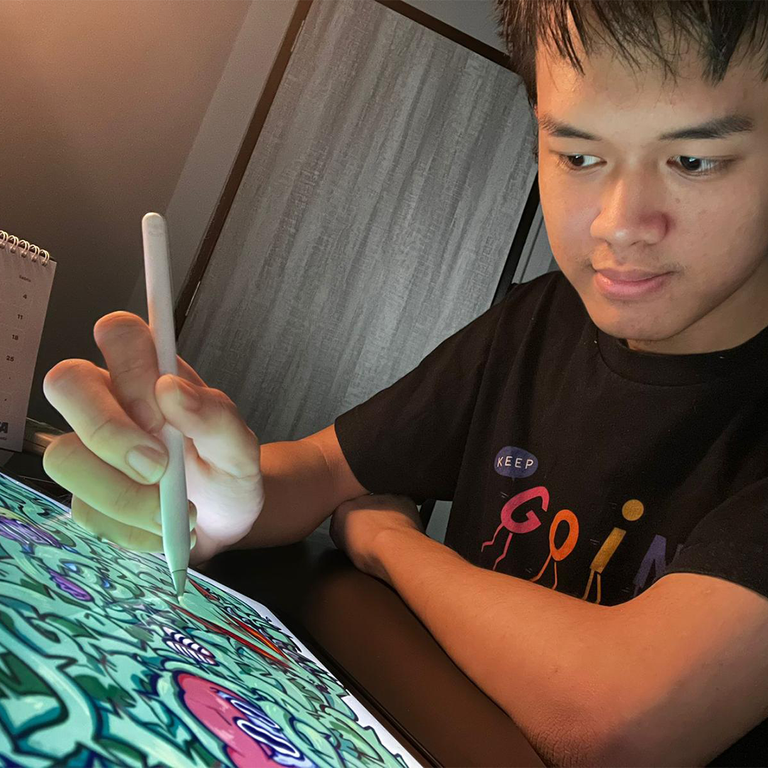 Young man uses a stylus to draw detailed green artwork on a tablet screen.