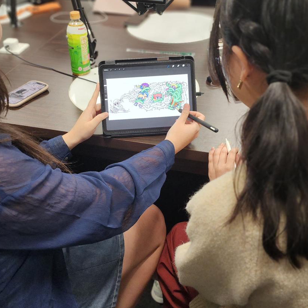 Two people use a tablet to create a colorful digital illustration with a stylus.