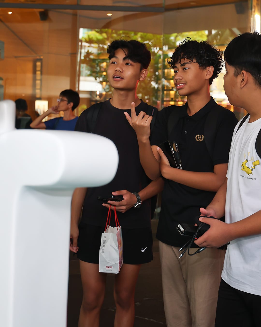 Three teenage boys standing together, looking and gesturing toward an unseen exhibit.