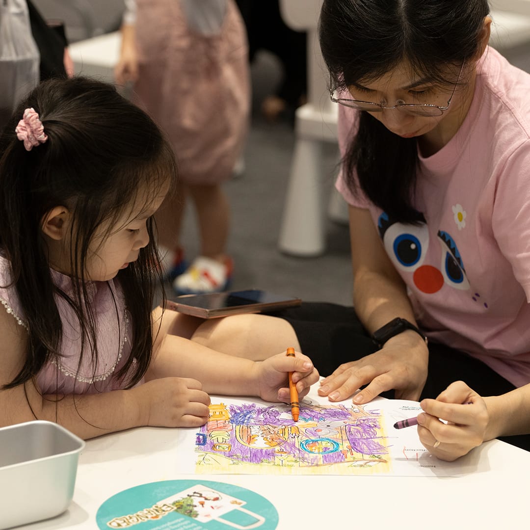 Child and adult coloring a worksheet together at an event table.