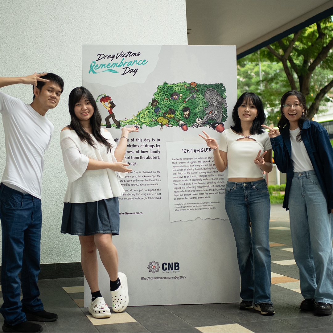 Four youths pose beside a CNB poster for Drug Victims Remembrance Day artwork.