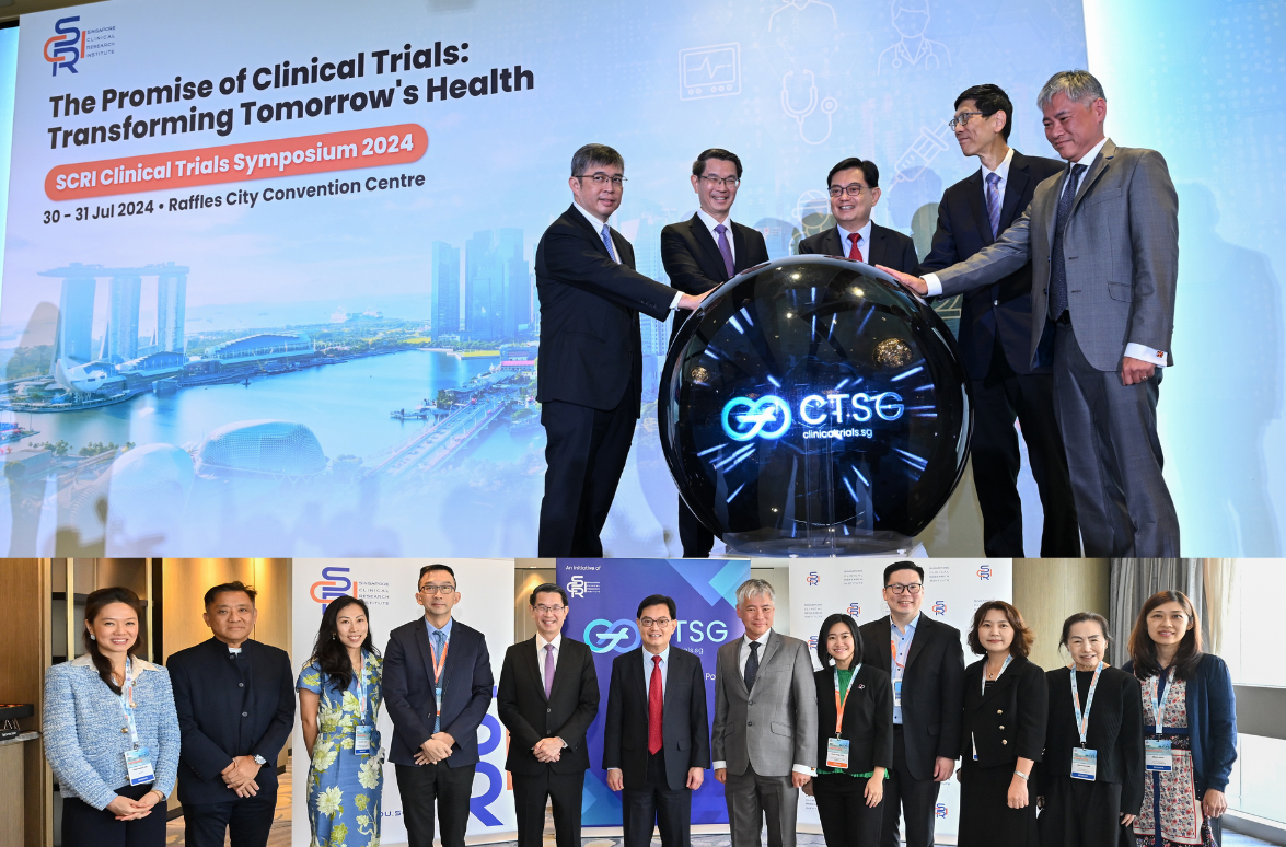 Groups of people in business attire stand in front of clinical trials symposium banners, with a futuristic display between them.
