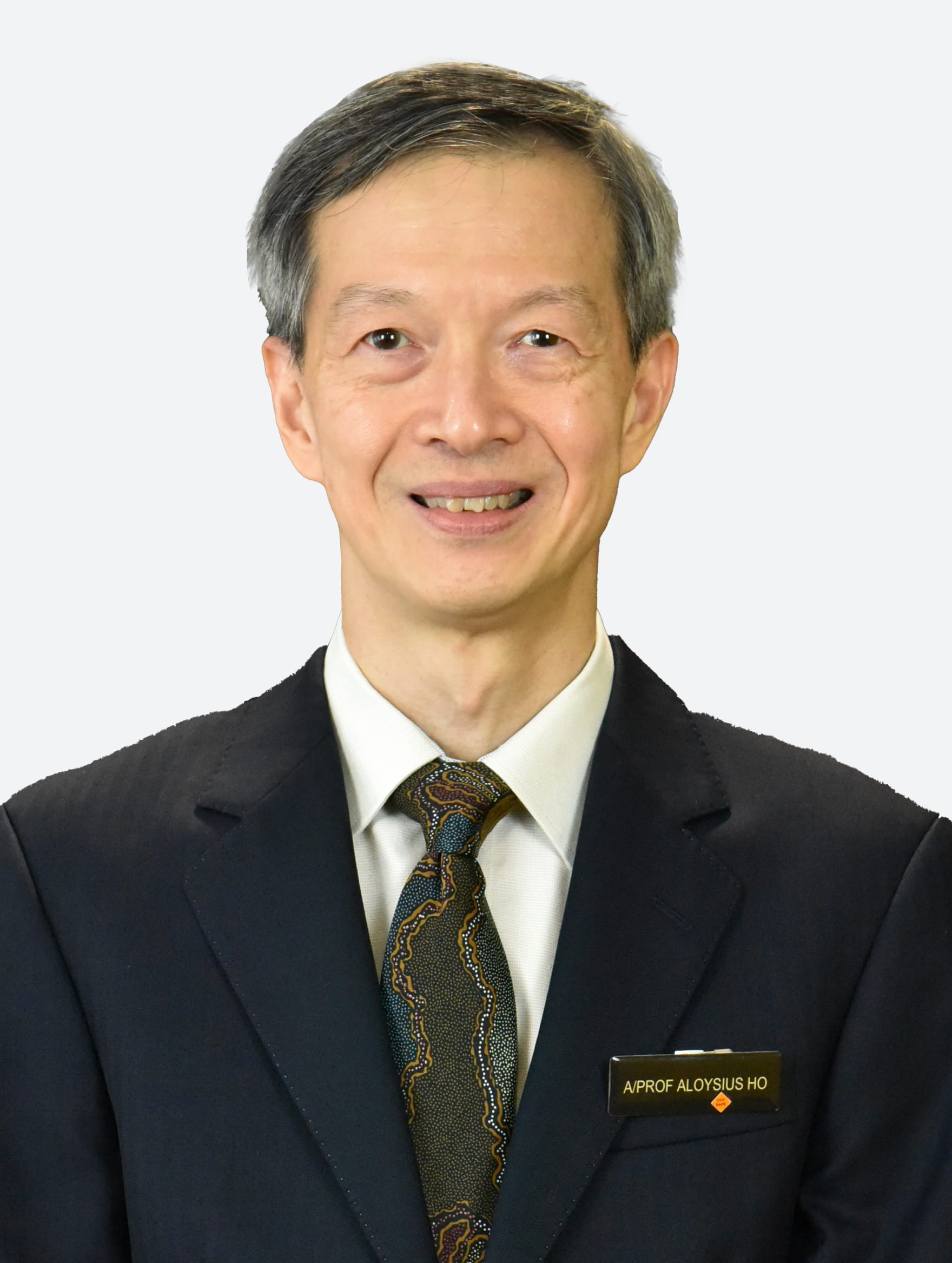 A man in a suit and tie wearing a name badge that reads "A/PROF ALOYSIUS HO".