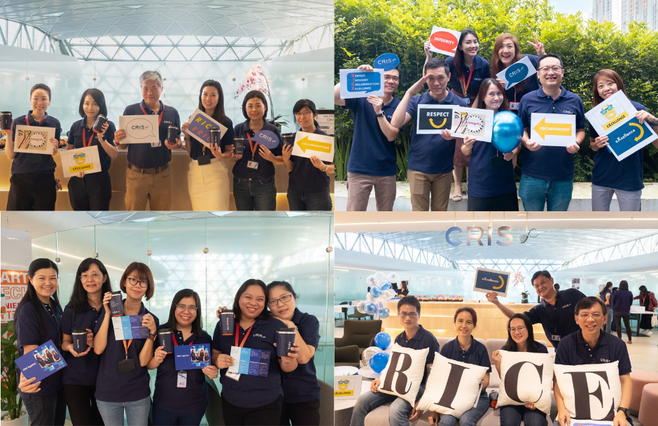 People holding various signs and booklets related to workplace values and corporate branding in a bright office setting.