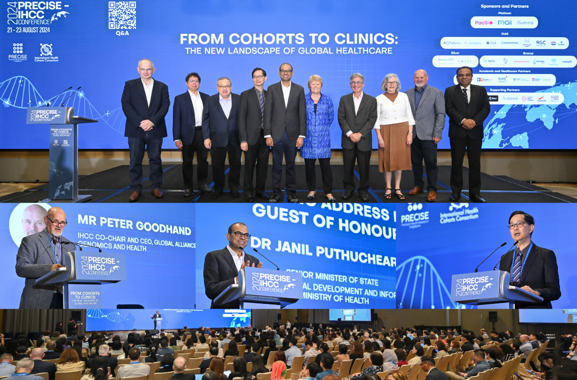 A group of people stand on stage, two men speak at podiums, and audience members sit facing a large screen.
