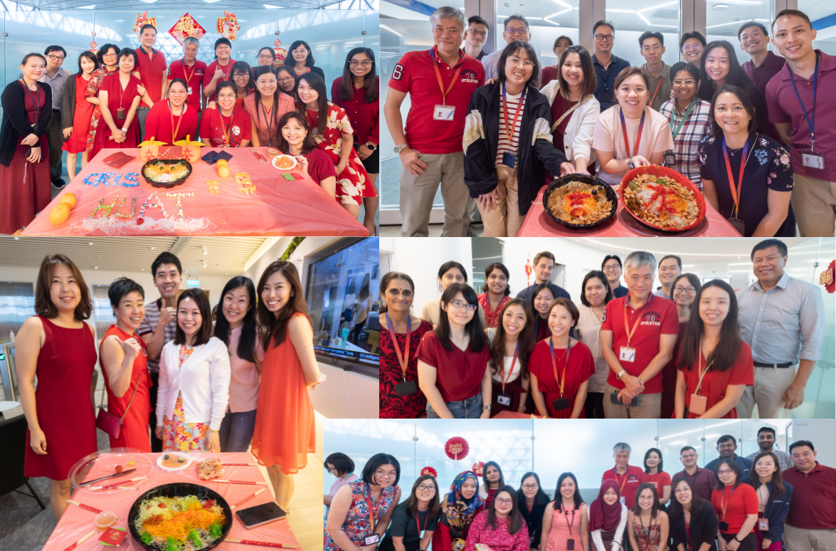 People standing around tables with decorative items and platters of colorful food dishes, all wearing red or casual attire.