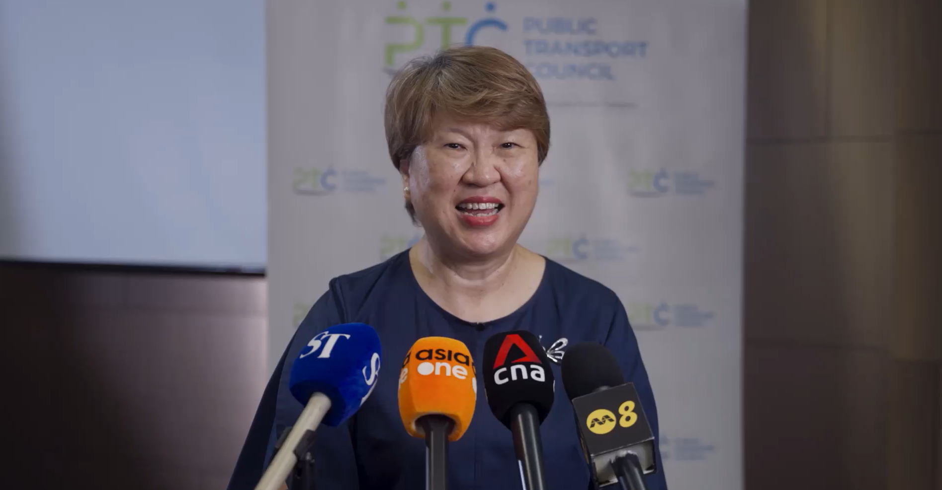 Ms Janet Ang giving an interview with microphone from different agencies