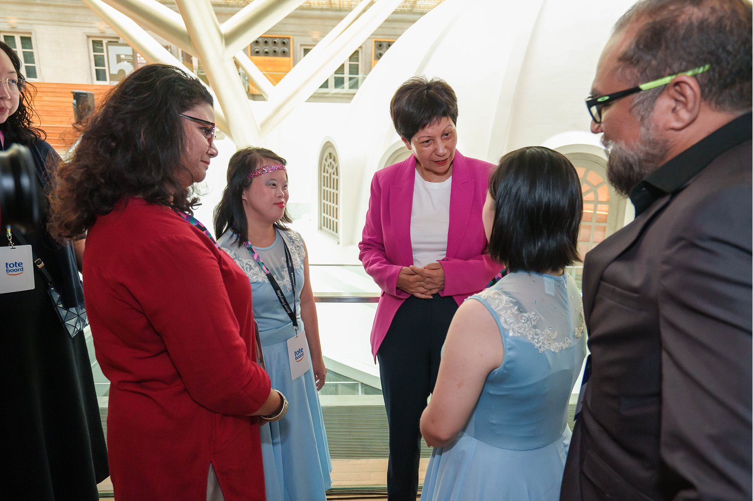 Second Minister for Finance and national Development Indranee Rajah in a pink blazer, talking to performers and staff.