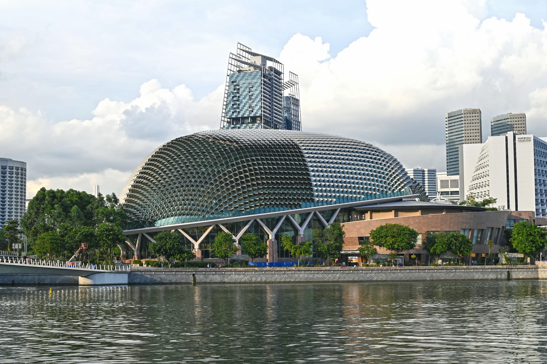 Singapore's Esplanade, a theater complex with a spiky dome, on a riverfront with city buildings behind.