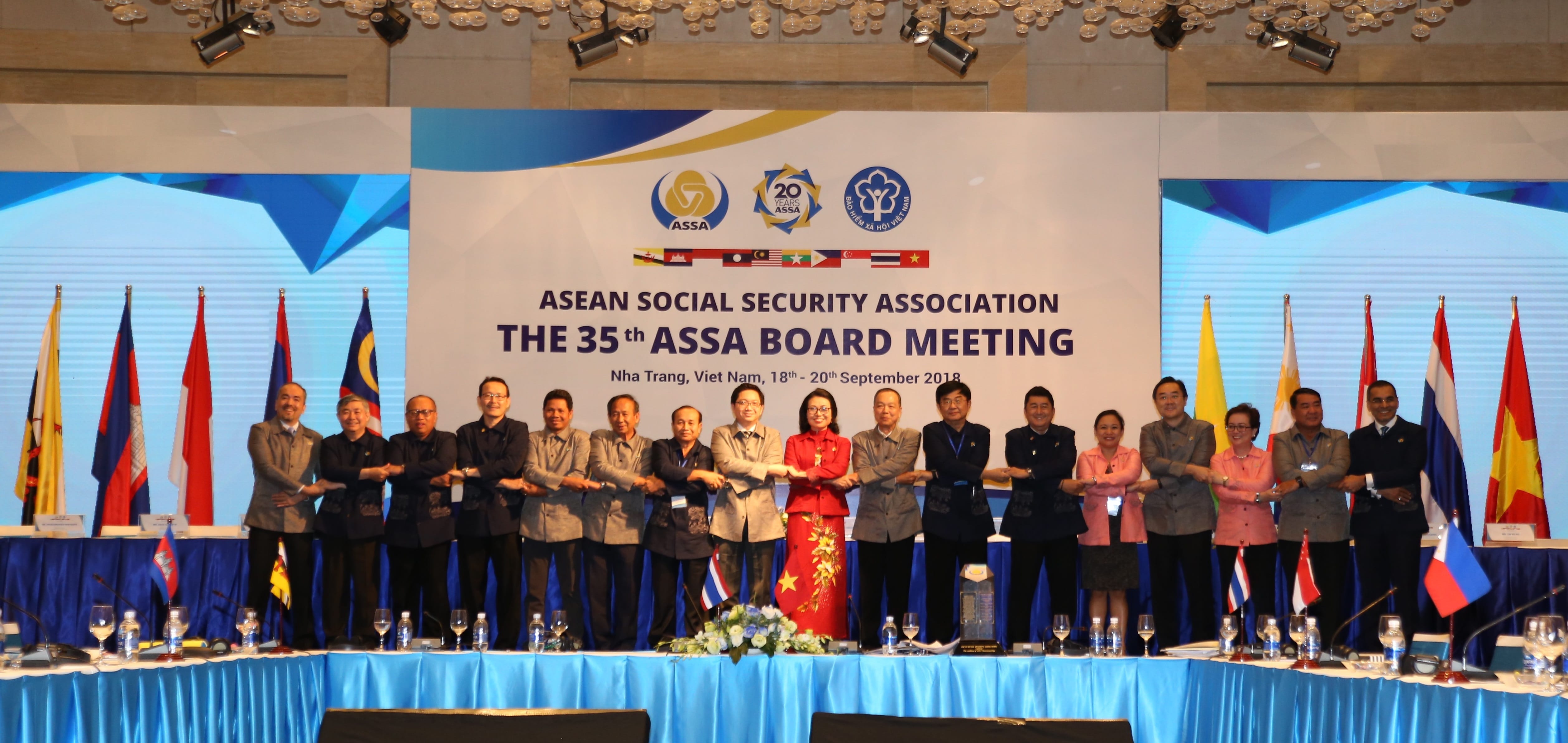 A group of people stand in front of flags, arms crossed, under a banner for the ASEAN Social Security Association's 35th board meeting.