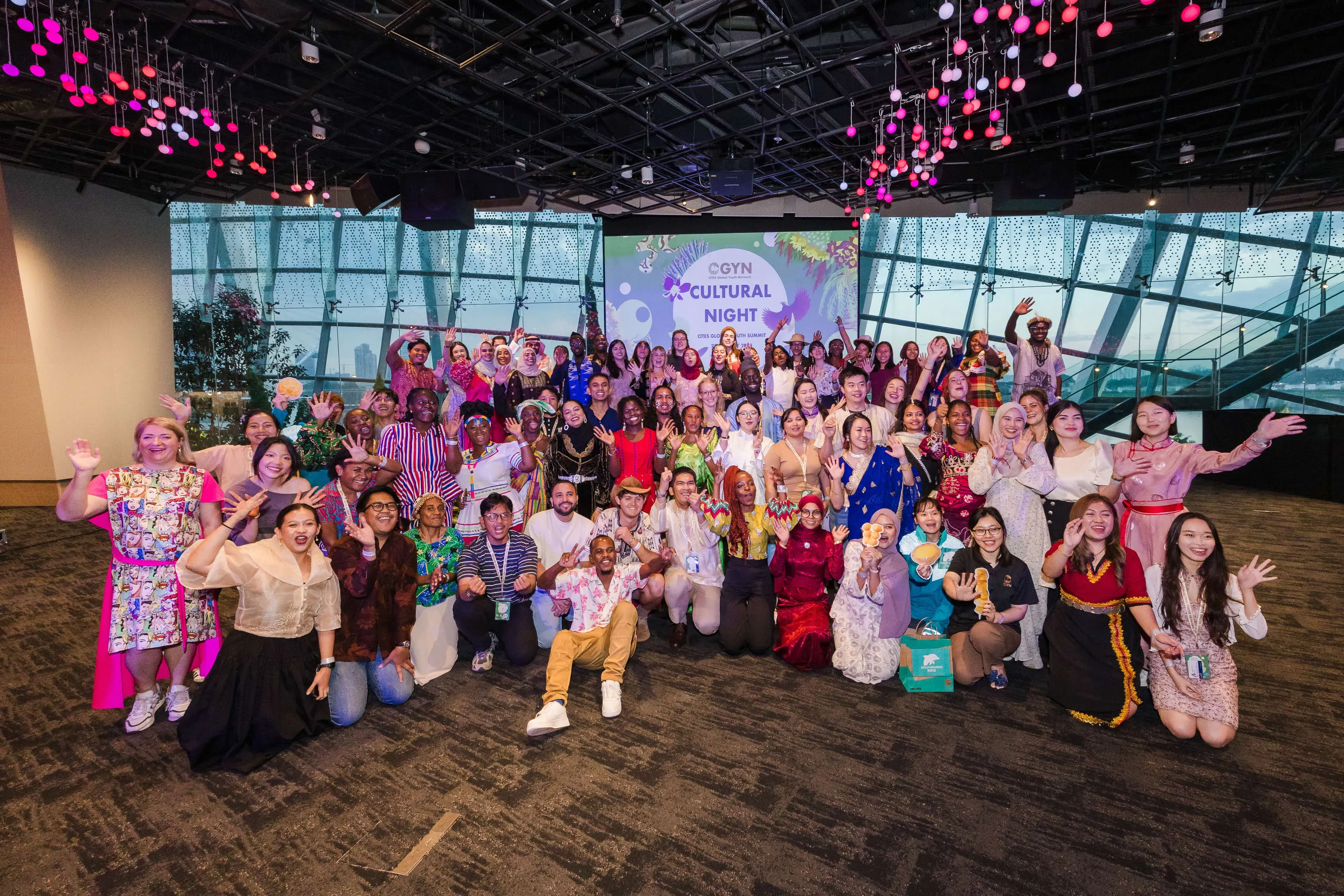A photograph of a large amount of people wearing cultural clothing in front of a projector that says CGYN Cultural Night