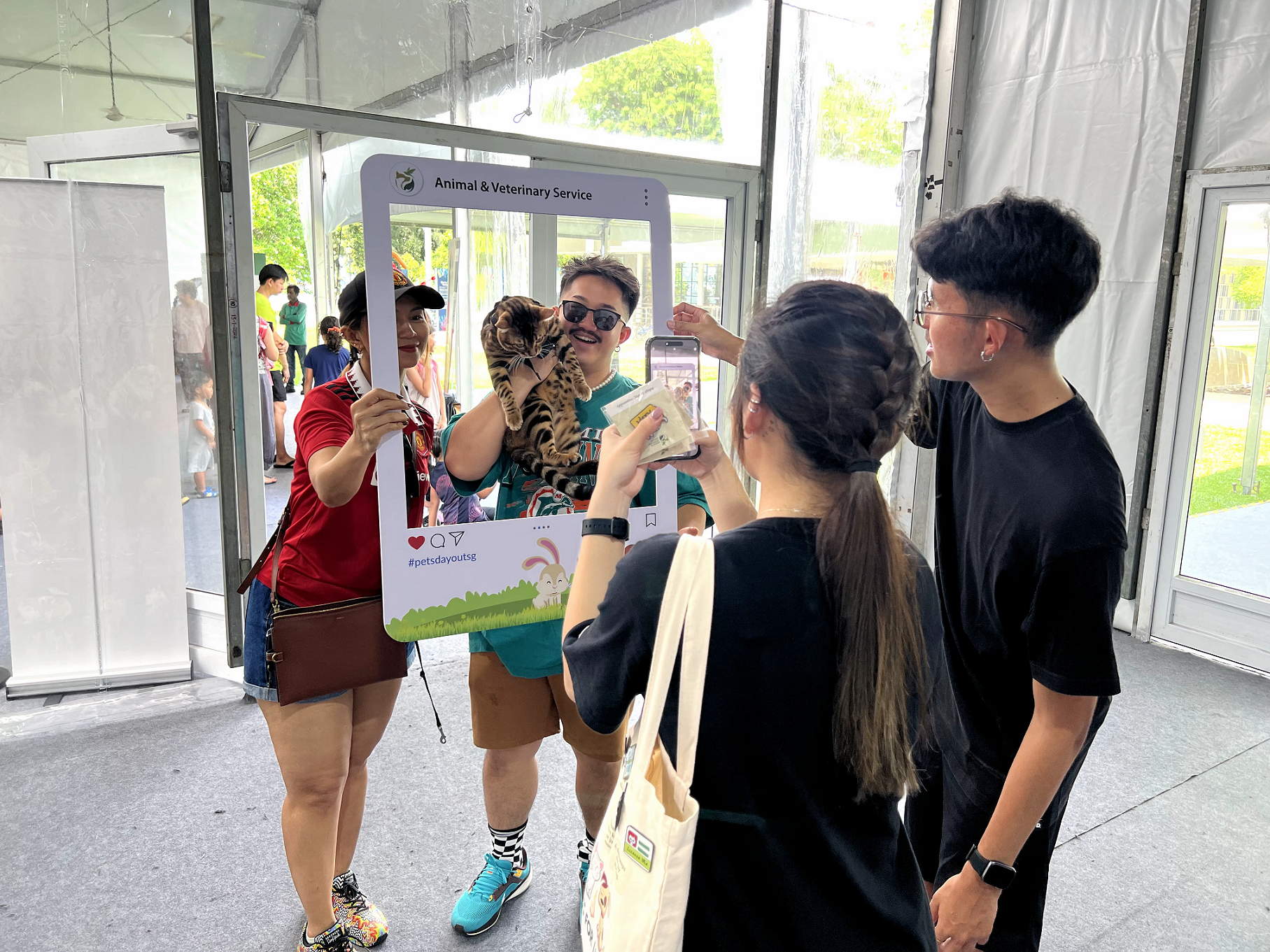 A photograph of 2 pet owners taking a photo with their cat at a photobooth