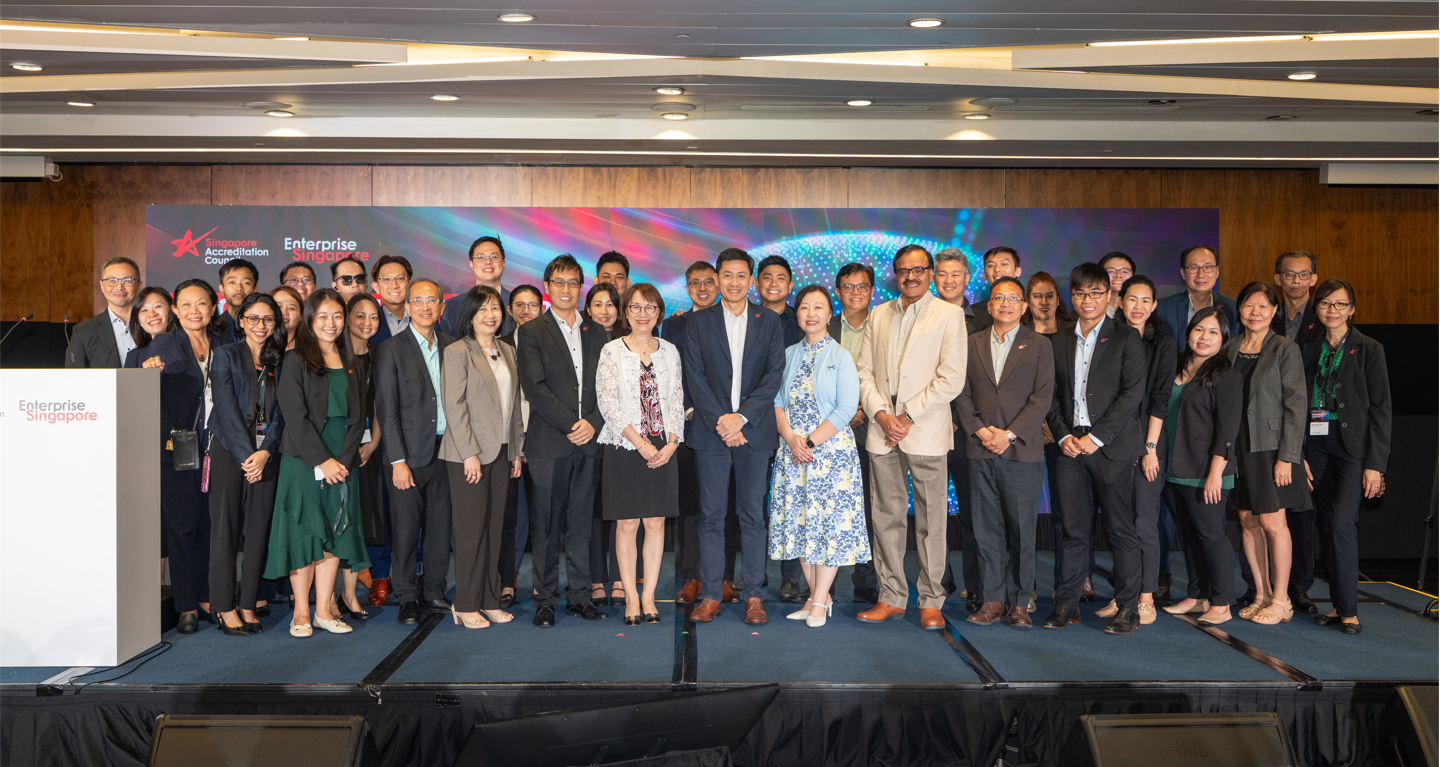 Large group of professionals posing on a stage at an Enterprise Singapore event with a colorful backdrop.
