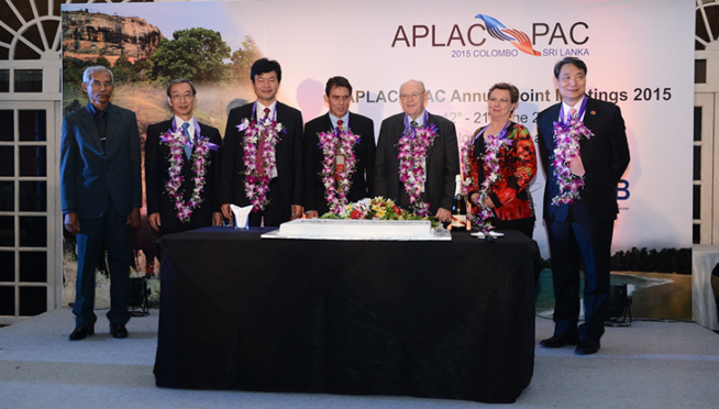 Seven people wearing floral leis stand before a banner reading APLAC PAC Annual Joint Meetings 2015 Colombo Sri Lanka.