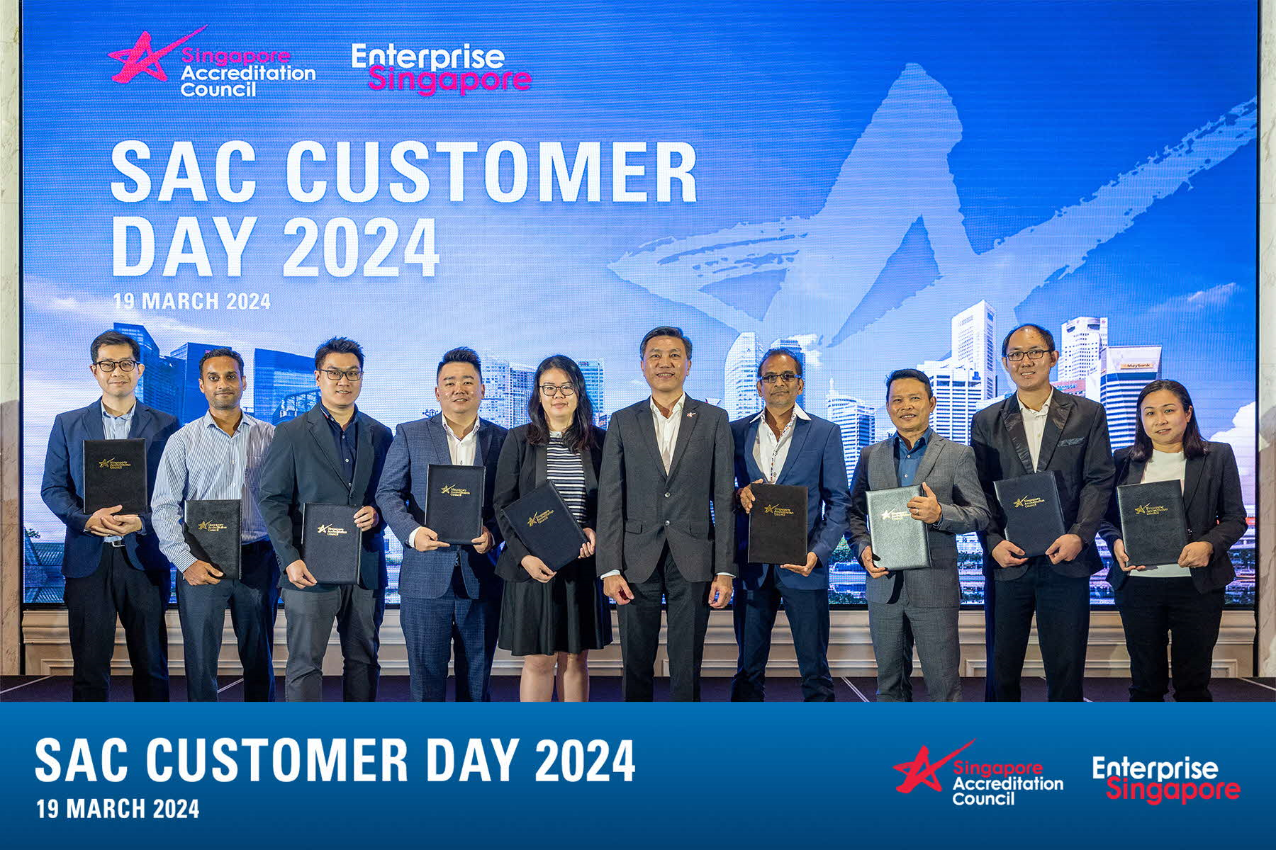 Ten people in suits holding certificates on stage under a SAC Customer Day 2024 backdrop, dated 19 March 2024.