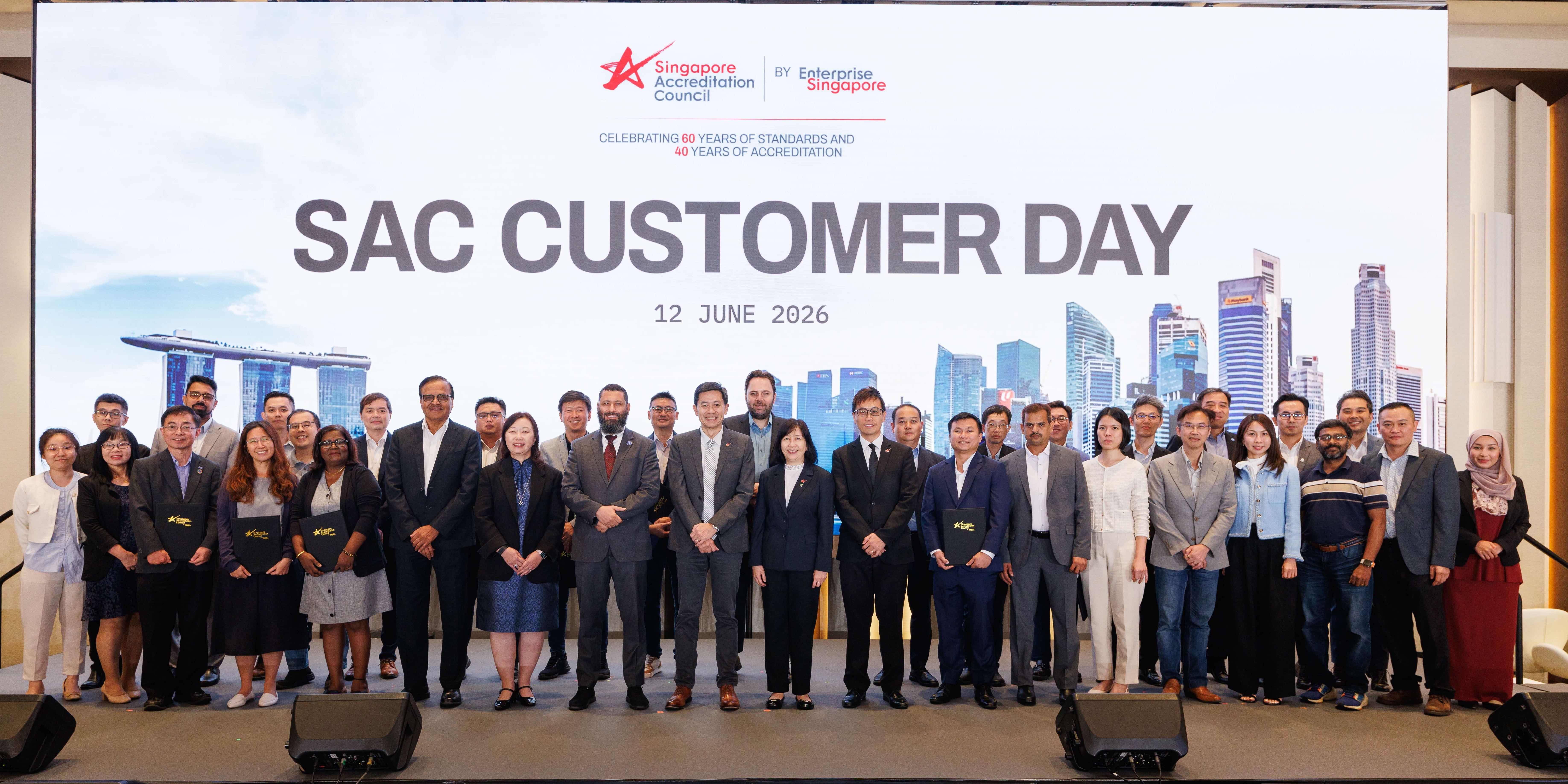 Group of people on stage under a screen reading SAC CUSTOMER DAY, 12 June 2026, with city skyline backdrop.