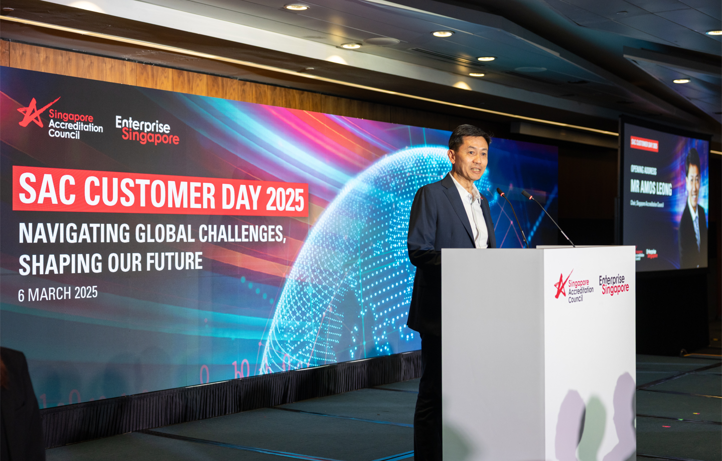 Man in a suit speaks at a podium at SAC Customer Day 2025 on 6 March 2025 in Singapore.