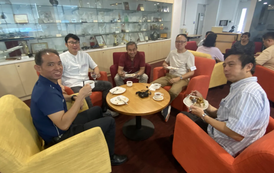 a group of participants sitting at a round table smiling at the camera