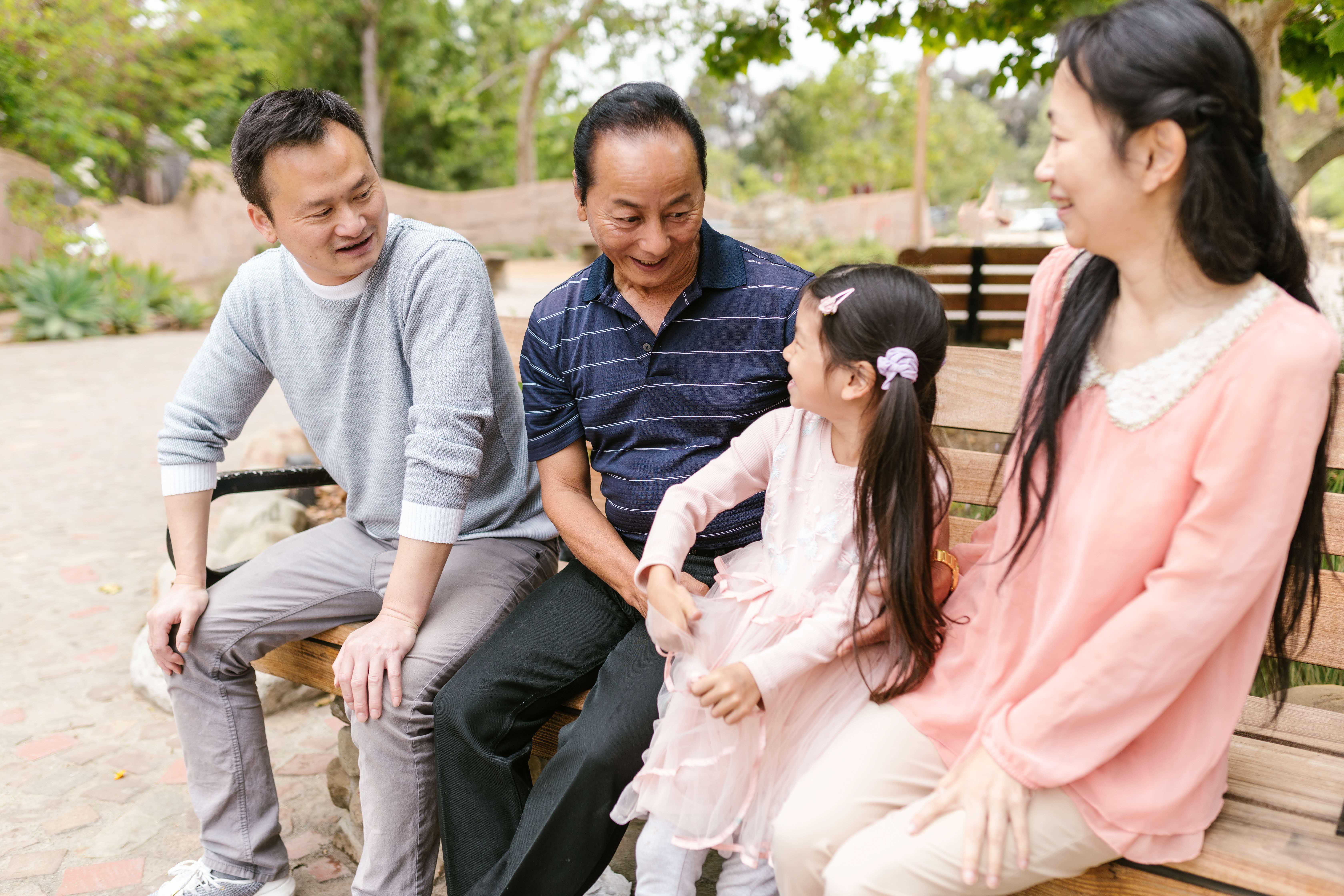 3 generations of people talking to each other on the couch, with a focus on the grandfather talking to his granddaughter
