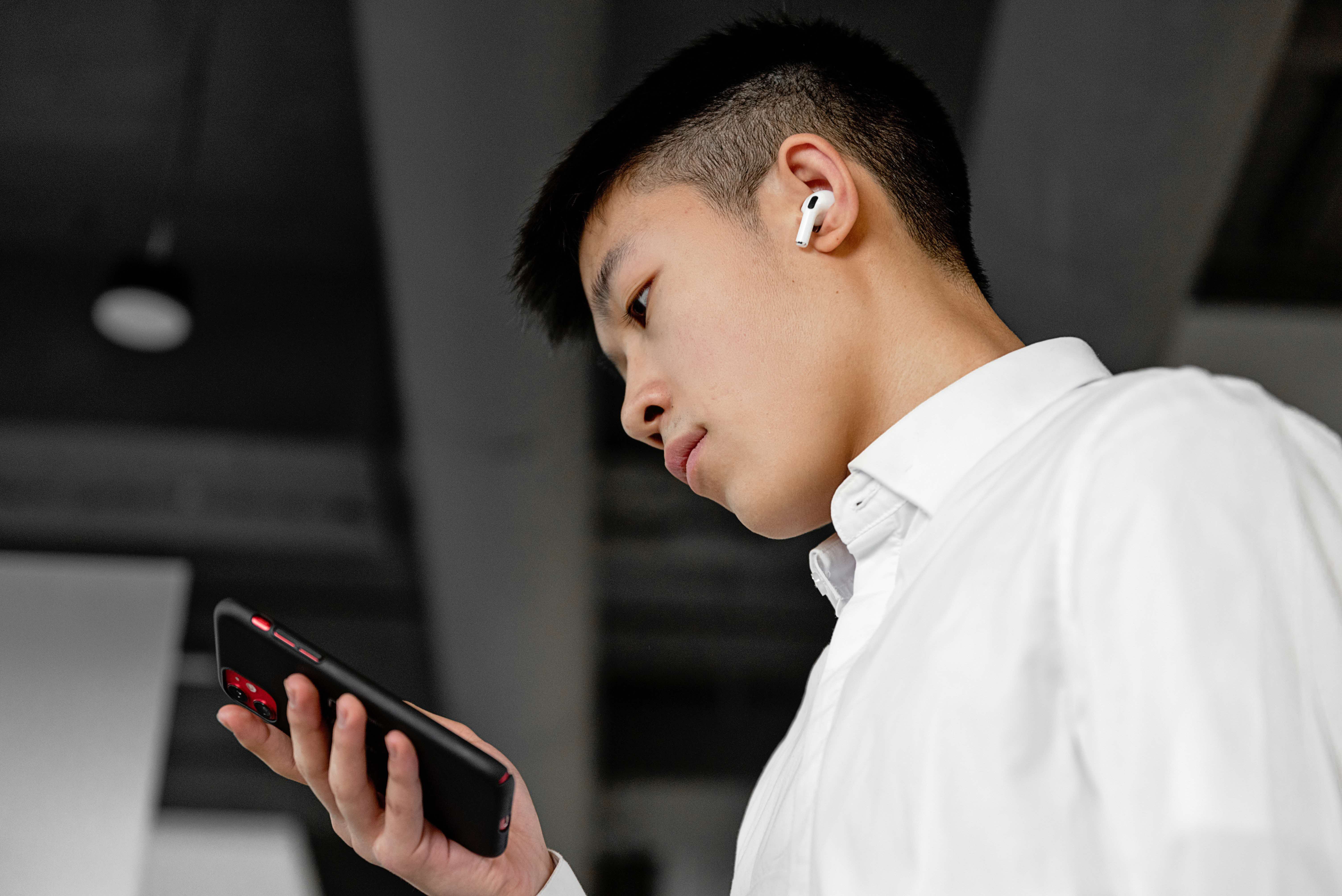 Asian man wearing airpods and looking at his phone
