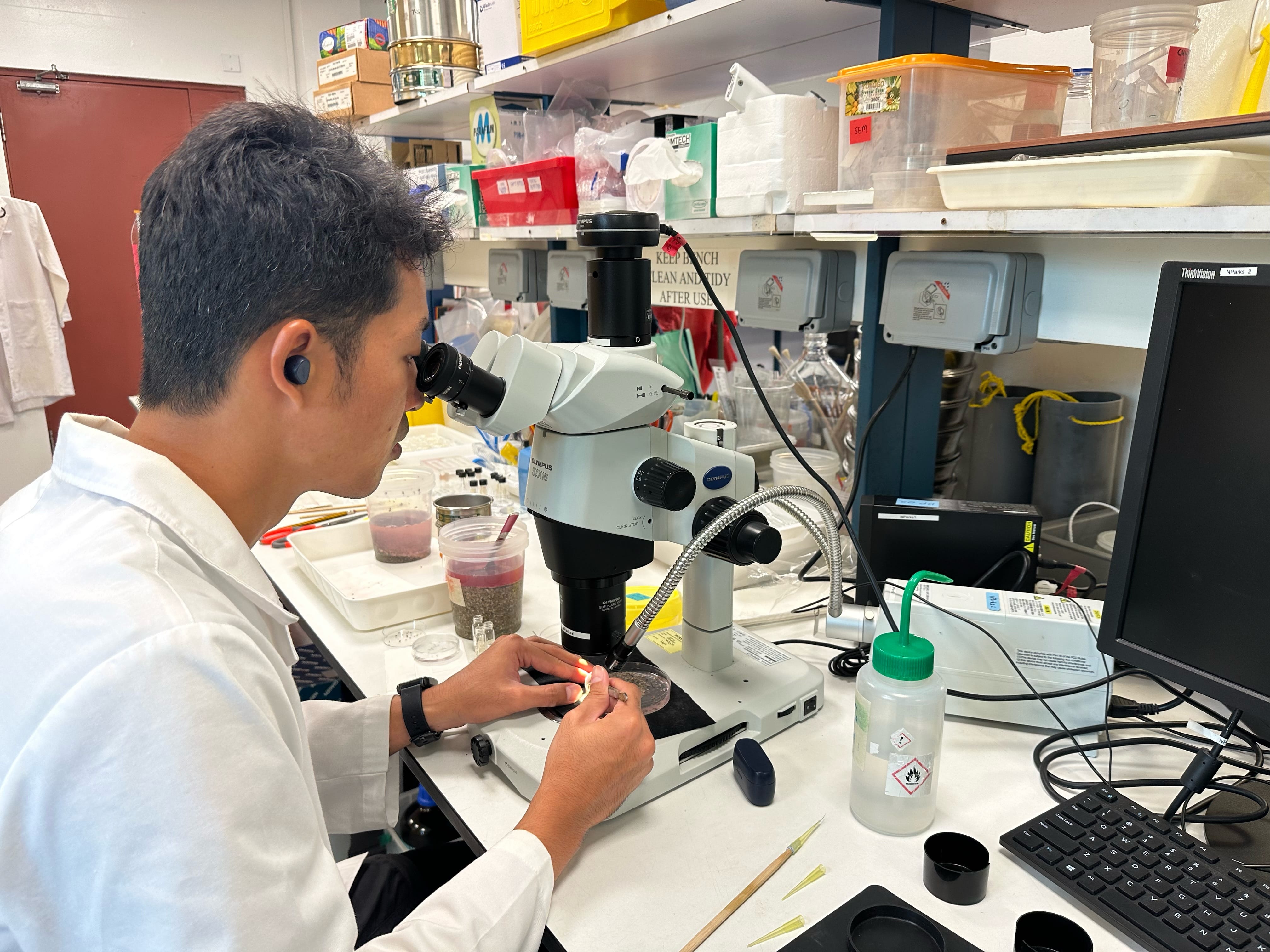A man in a white scientist coat looking through a microscope