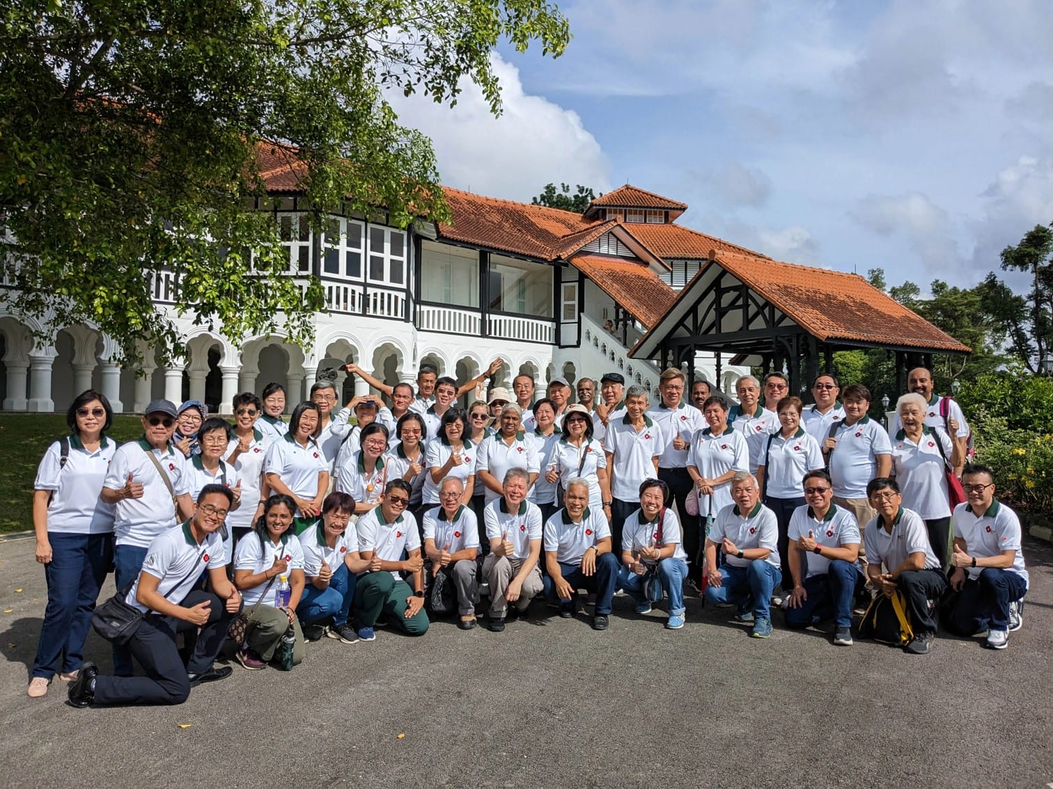 Group photo of many CIB Ambassadors in their ambassador polo shirts in front of an old colonial building in Botanic Gardens