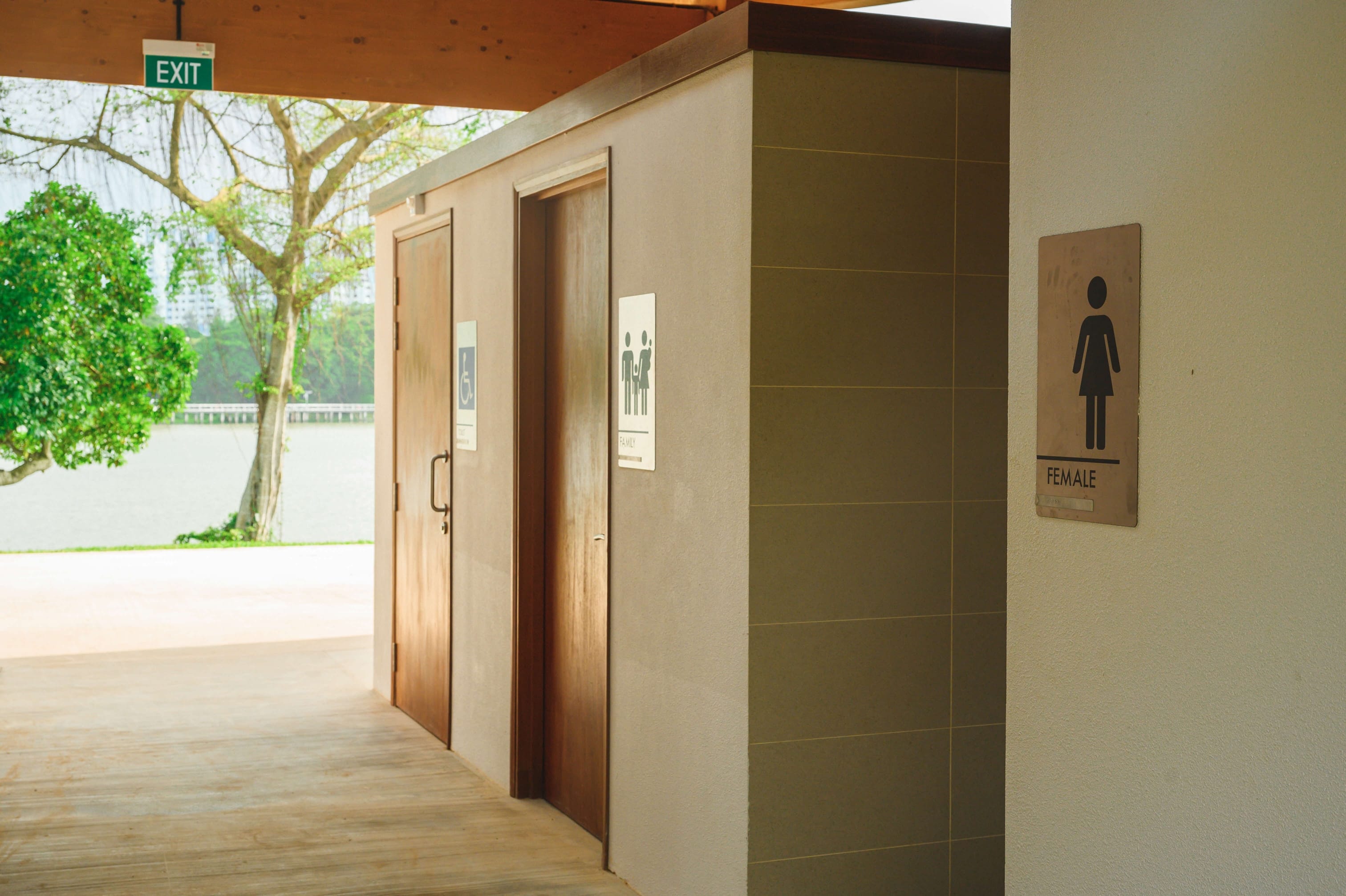 Signs for female, family, and accessible restrooms are on the wall; an exit sign is above the doorway.