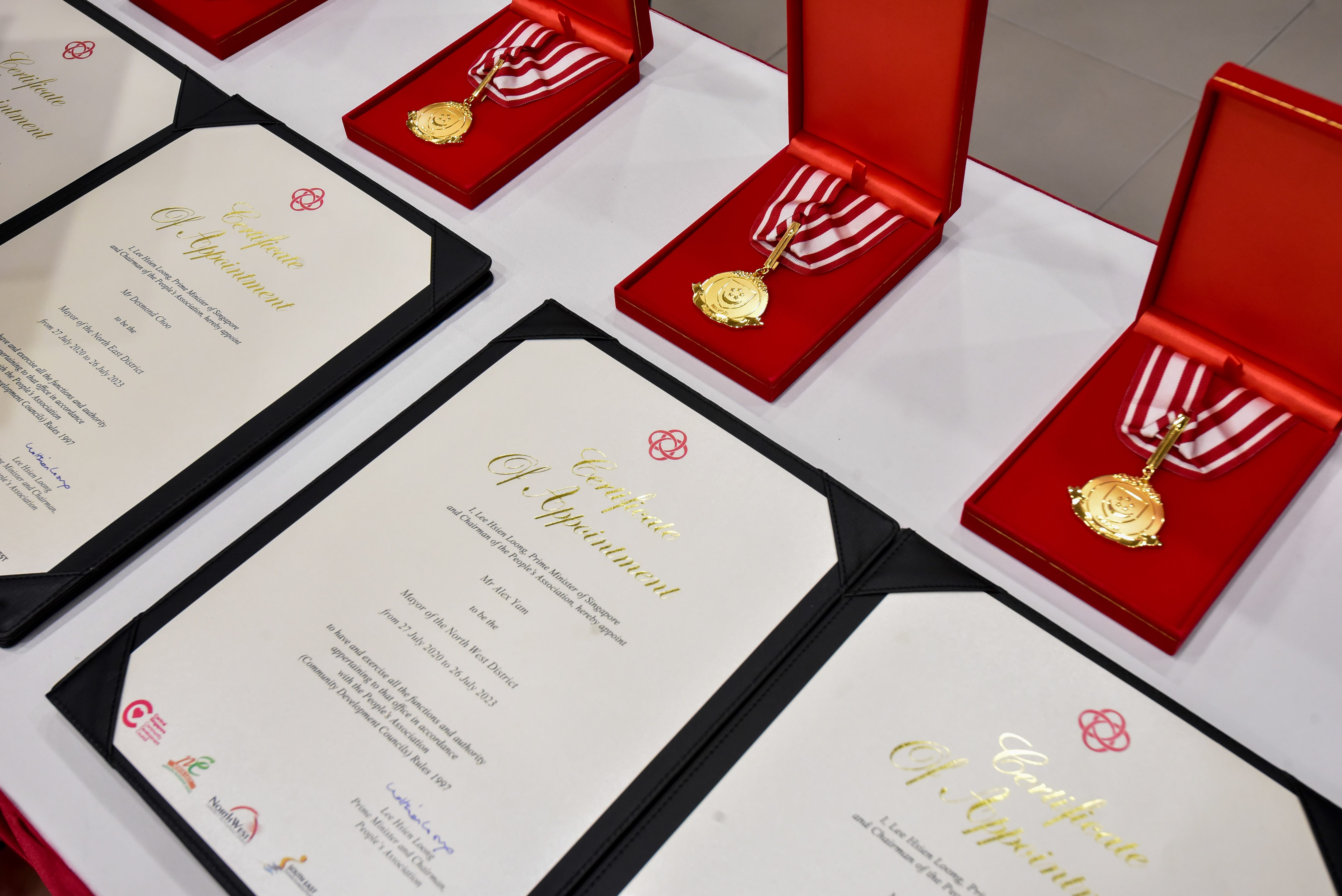 Several certificates of appointment and three medals in red cases are displayed on a table.