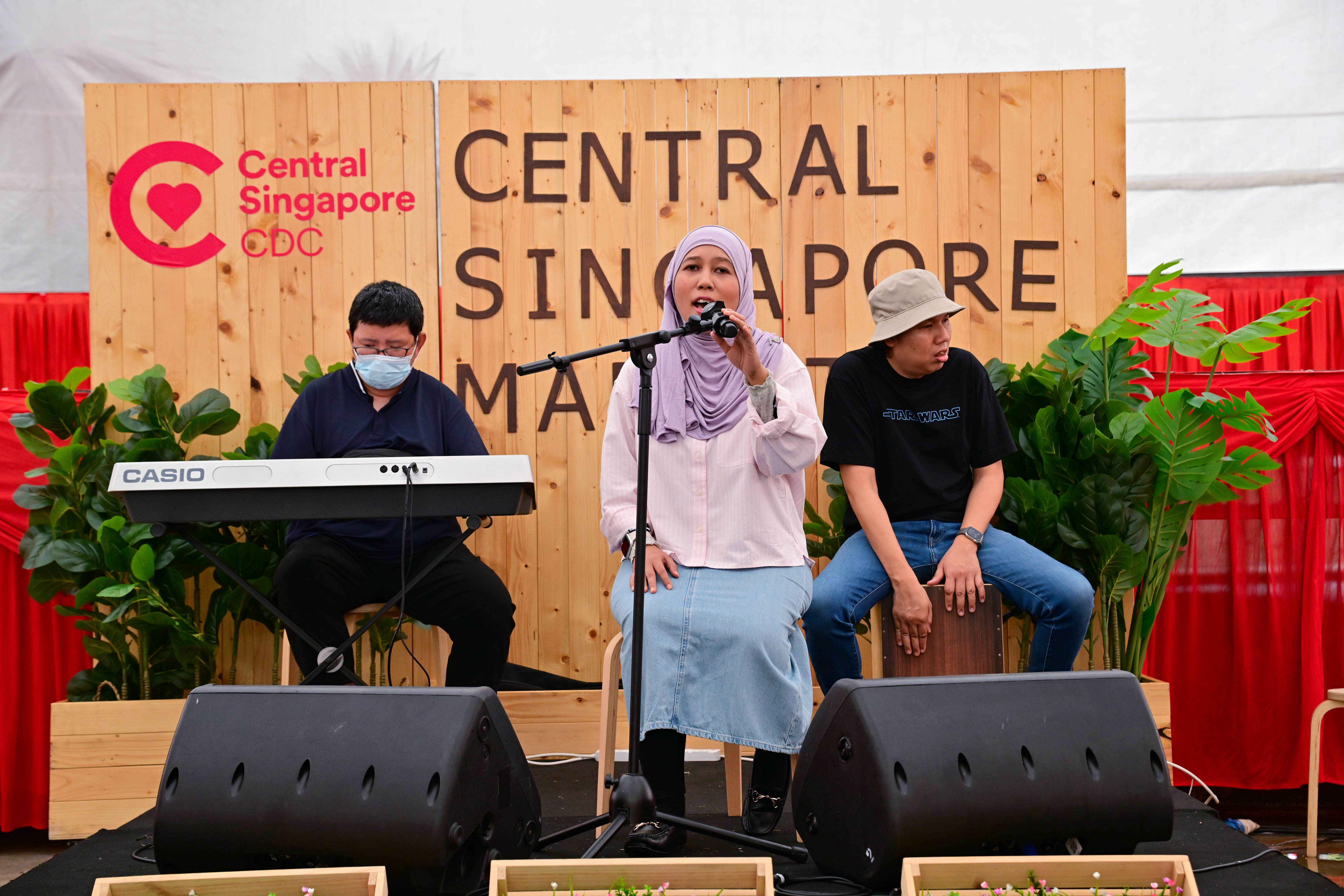 The photo shows three musicians with disabilities performing on stage.