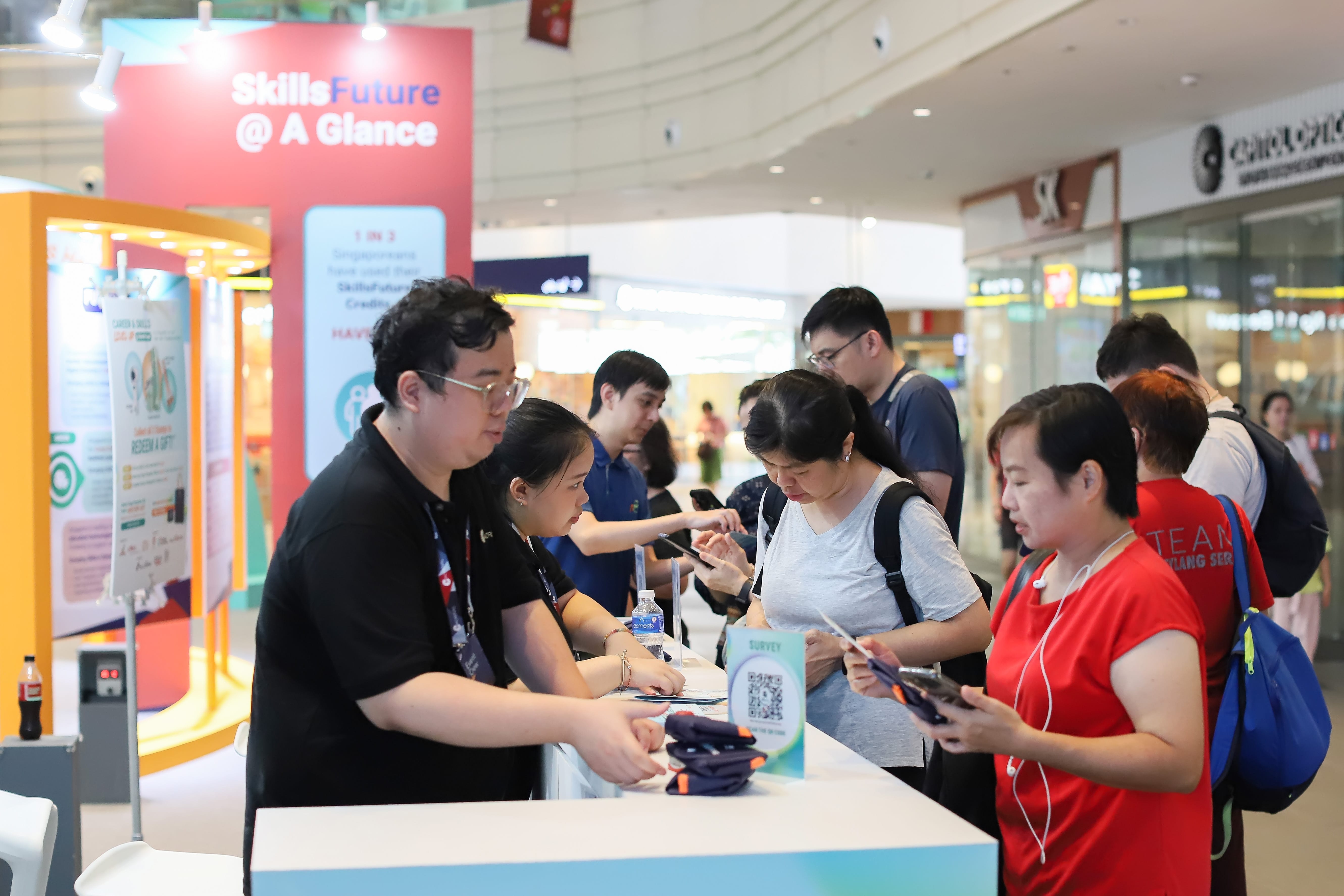 Visitors interacting with staff at an informational booth promoting SkillsFuture and career development opportunities