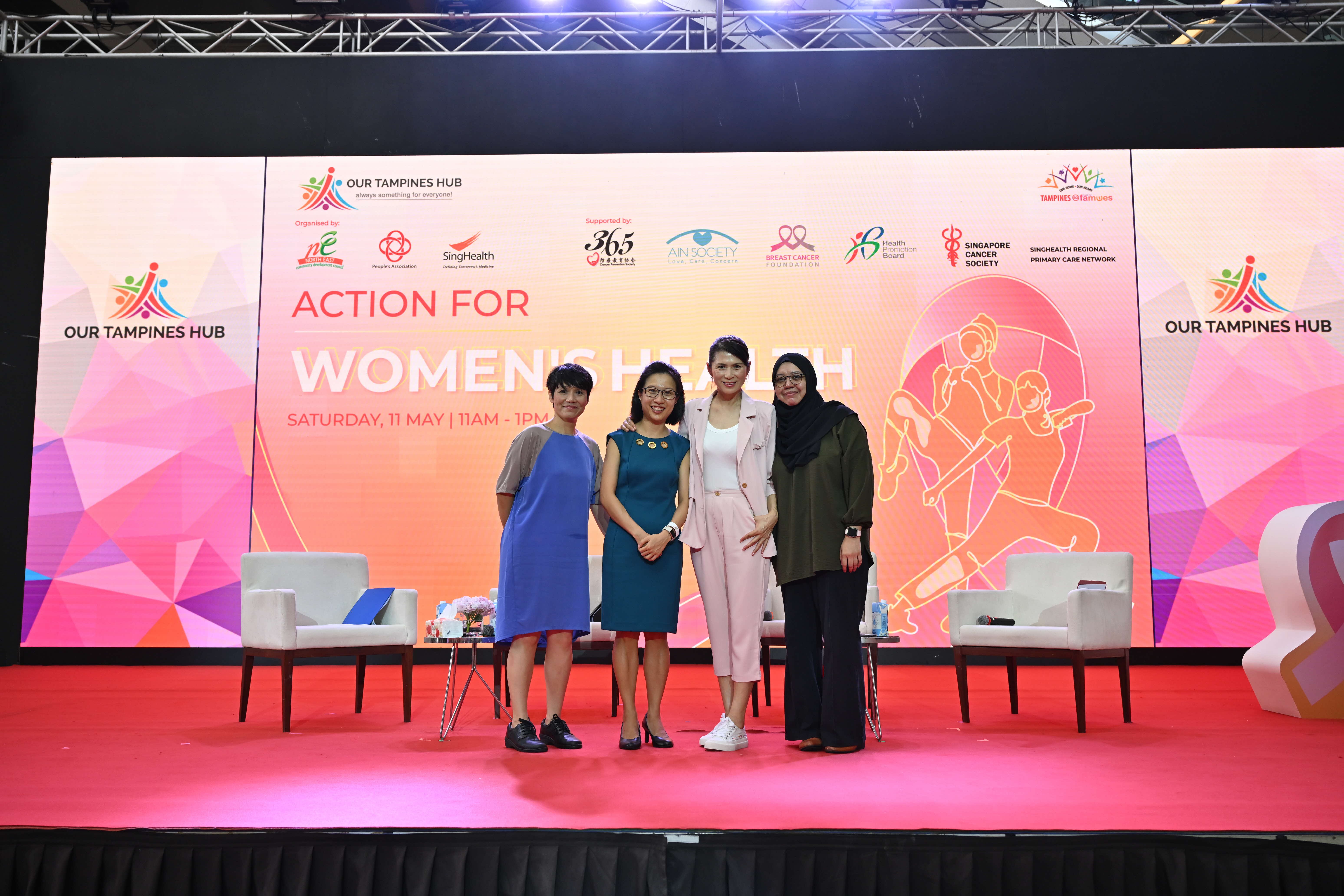 Four women stand side by side on a stage with "Action for Women's Health" signage in the background.