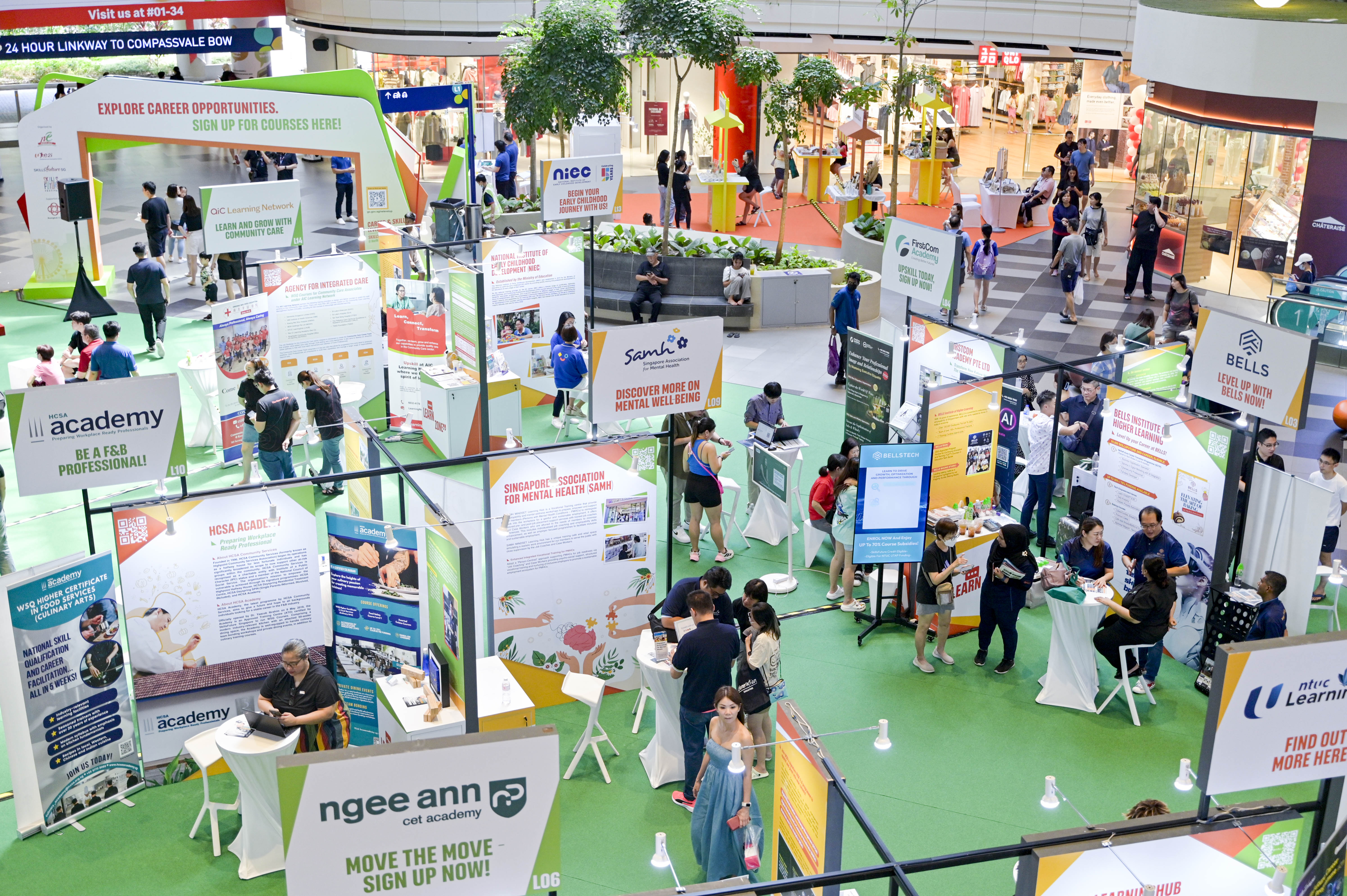 People exploring various educational booths at a career fair, with green and orange decor and informational displays.