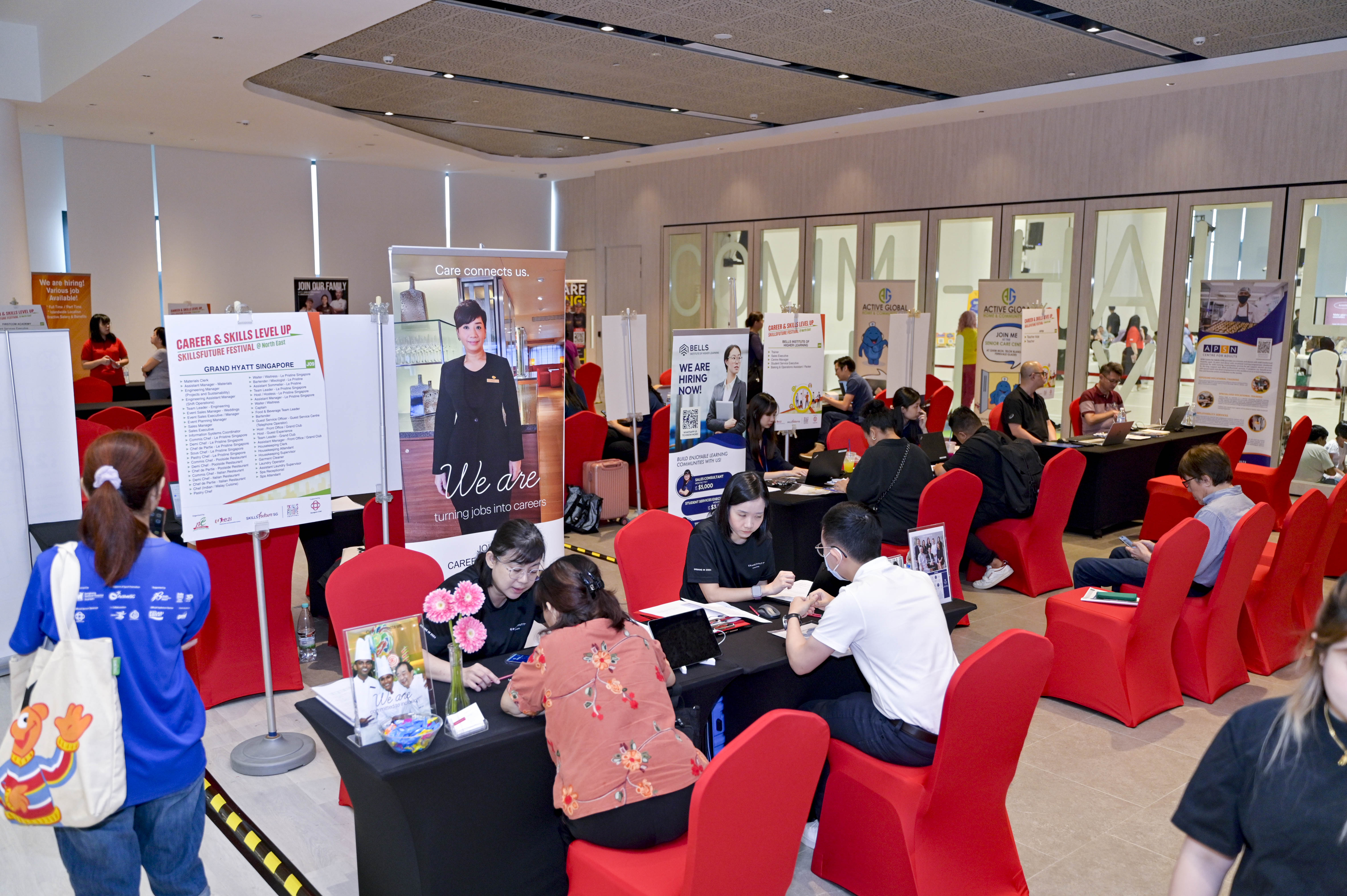 People are seated at tables in a conference room with multiple career and skills posters around.