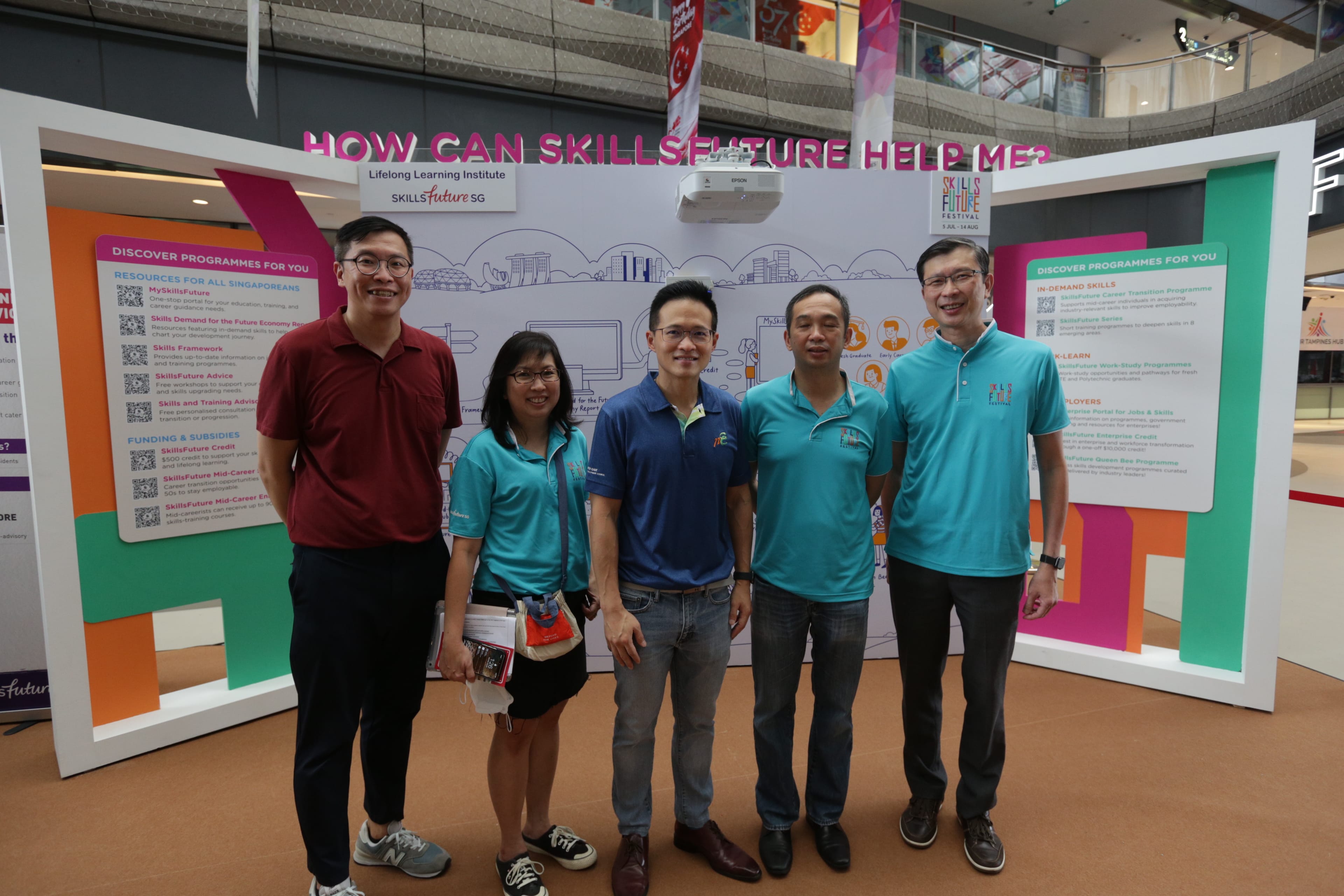 Group photo at a SkillsFuture Festival booth in a mall, promoting lifelong learning, skills upgrading, and career development opportunities.