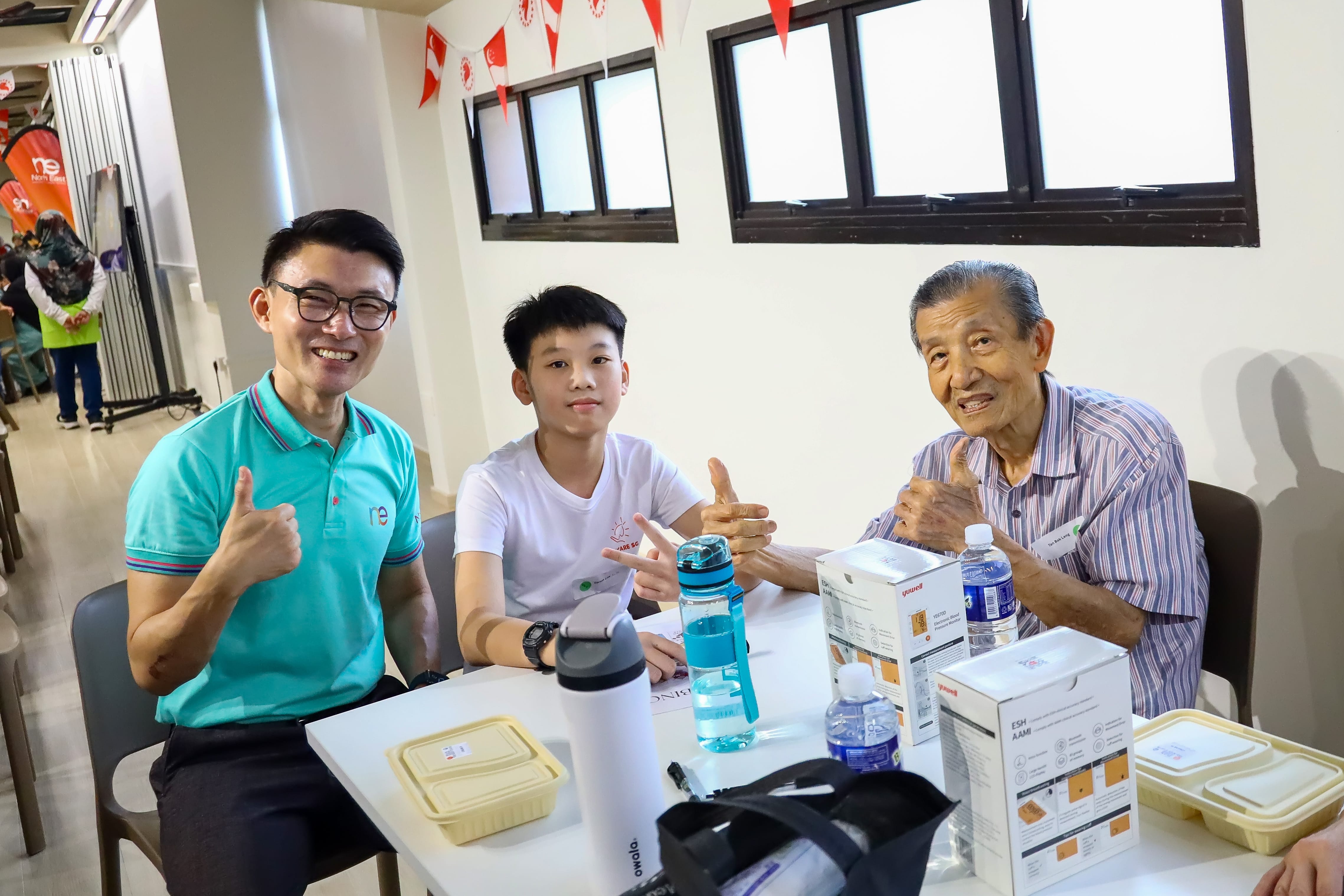 Young Health Hero posing for a photograph with a senior and Mr Baey Yam Keng.