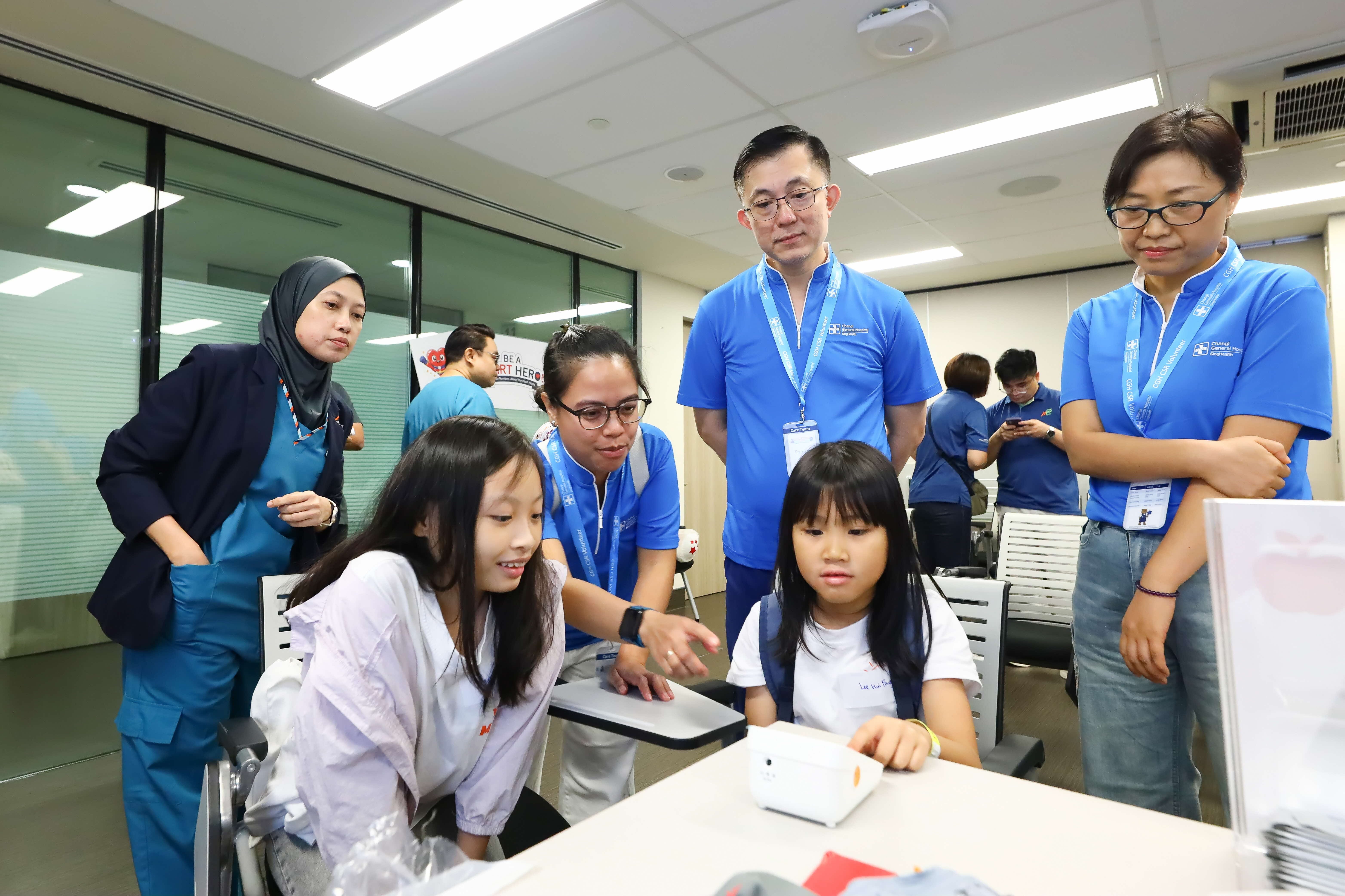 Young participants explored a blood pressure monitor with guidance from healthcare professionals at Changi General Hospital.
