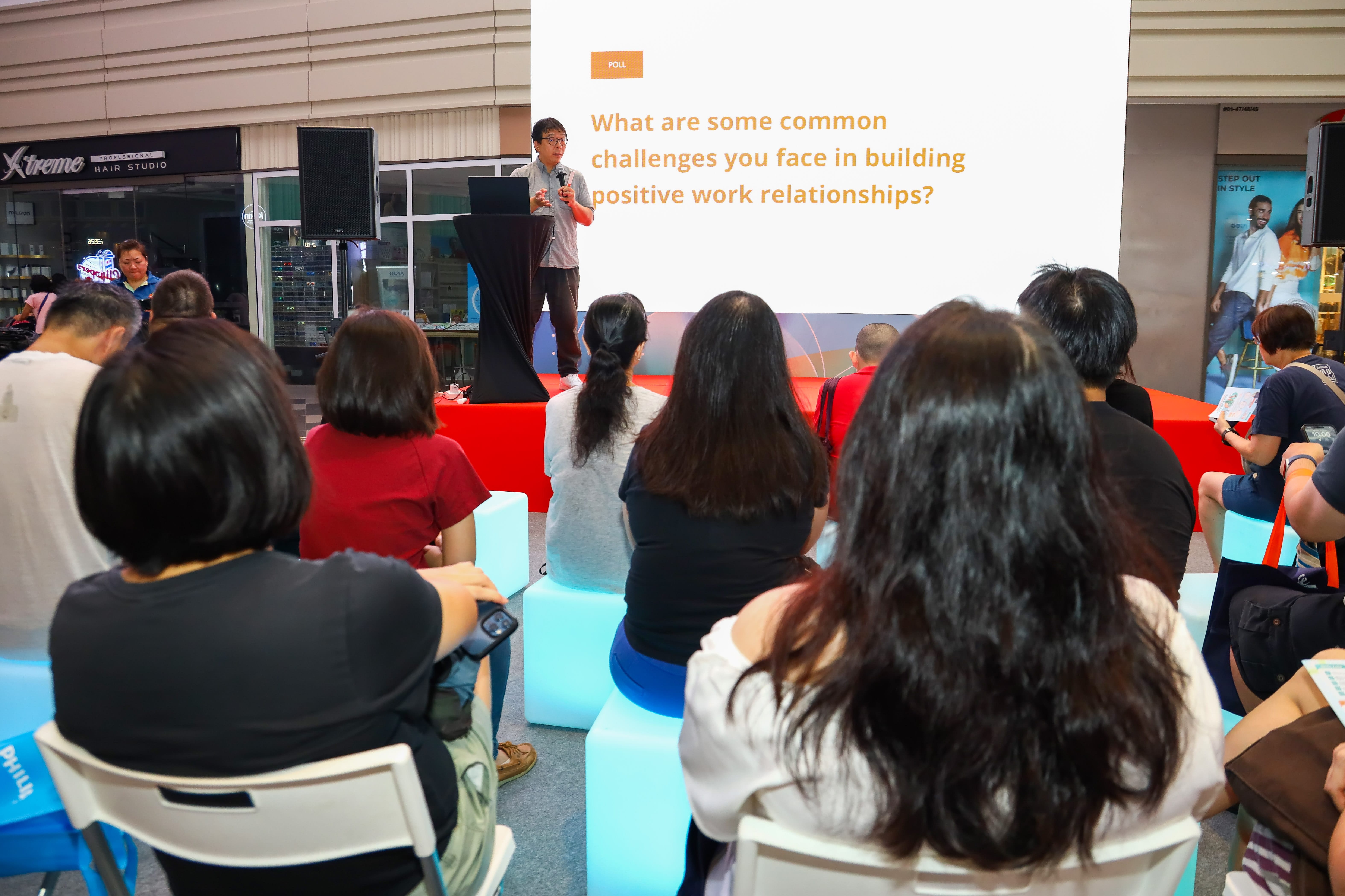 Speaker delivering a talk to an audience on building positive workplace relationships.