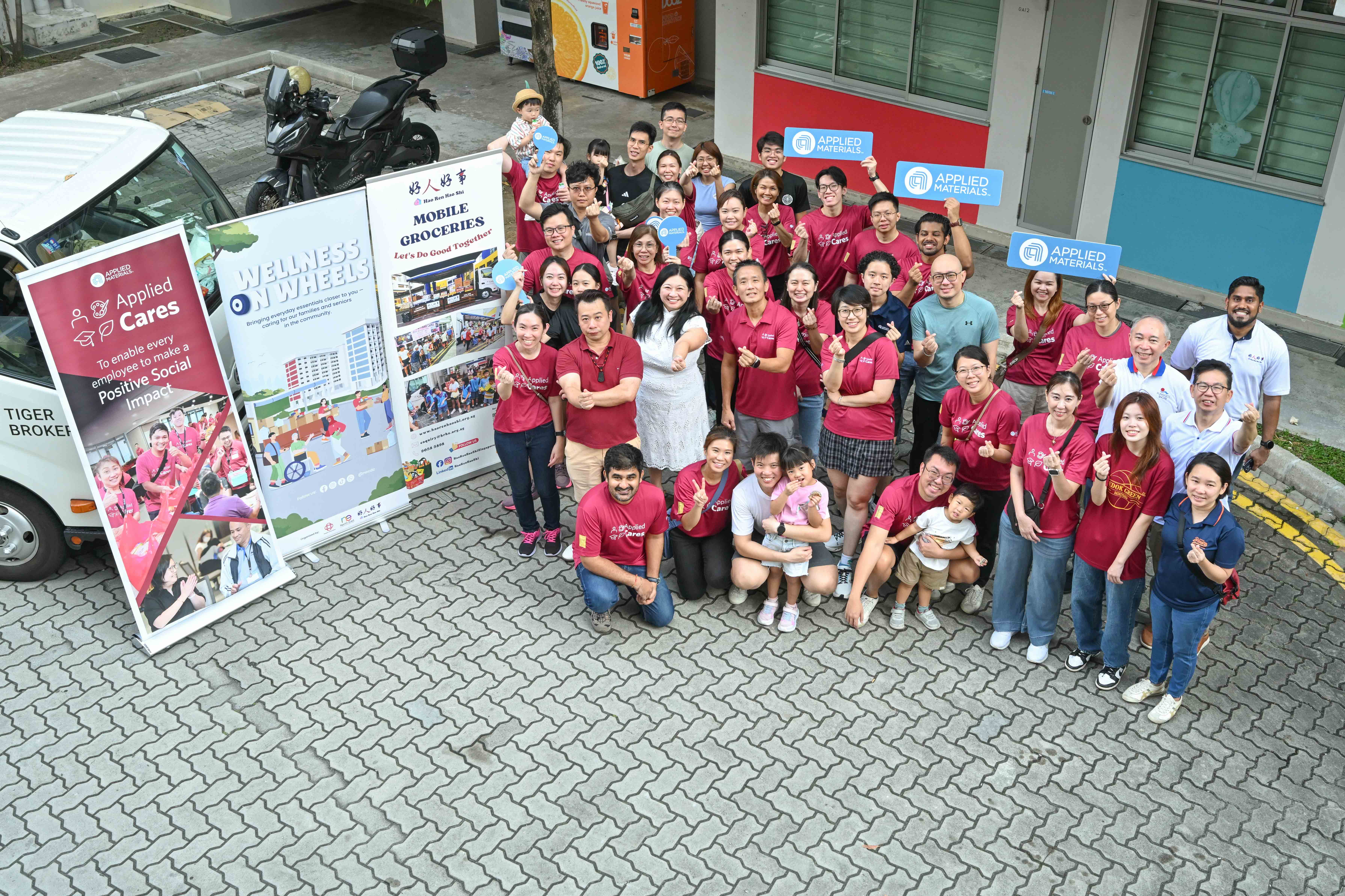 Volunteers from Applied Materials and Hao Ren Hao Shi posing for a group photograph beside the Wellness on Wheels and Mobile Groceries vehicles.