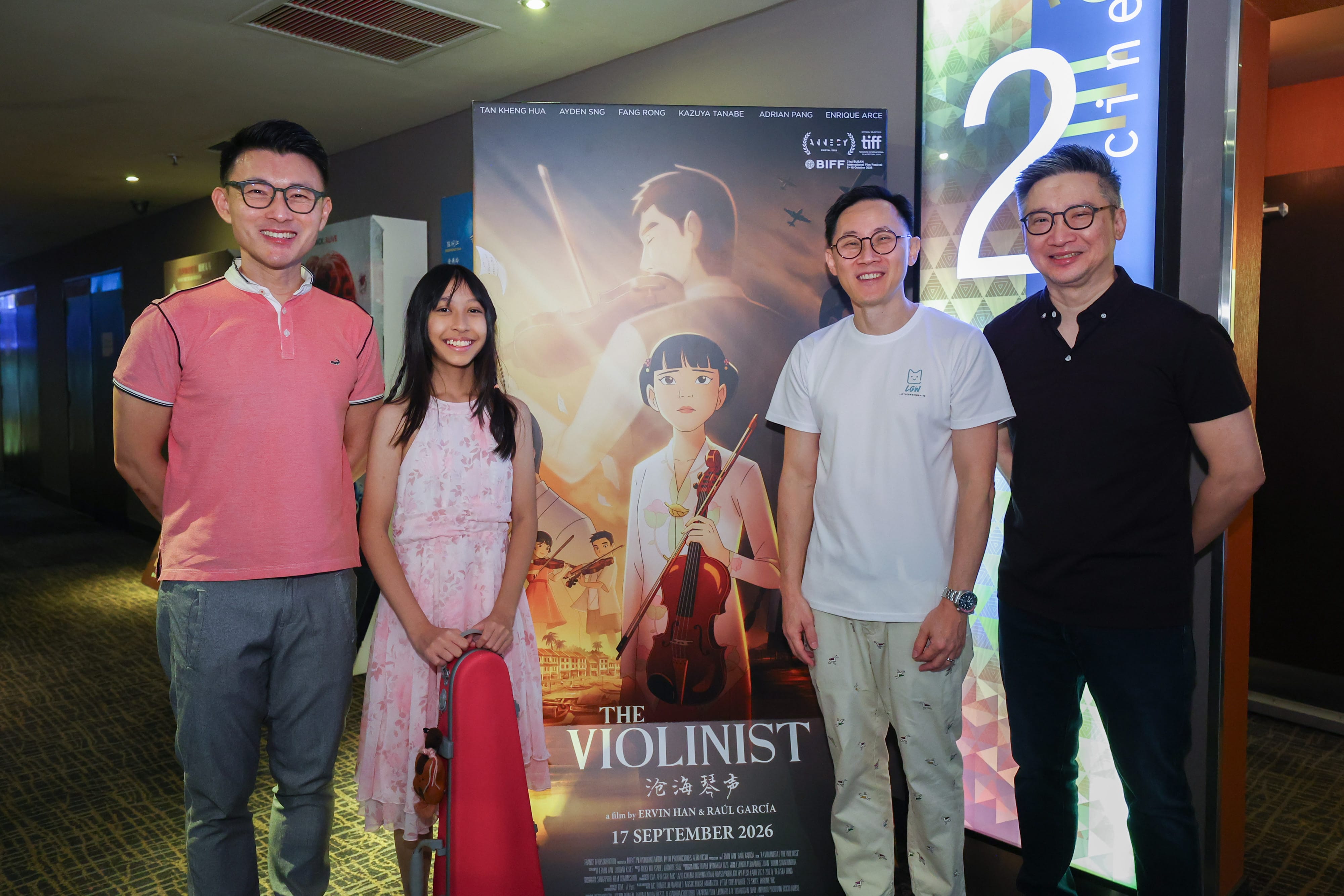 Group shot of Mr Baey Yam Keng, young violinist and producers in front of poster