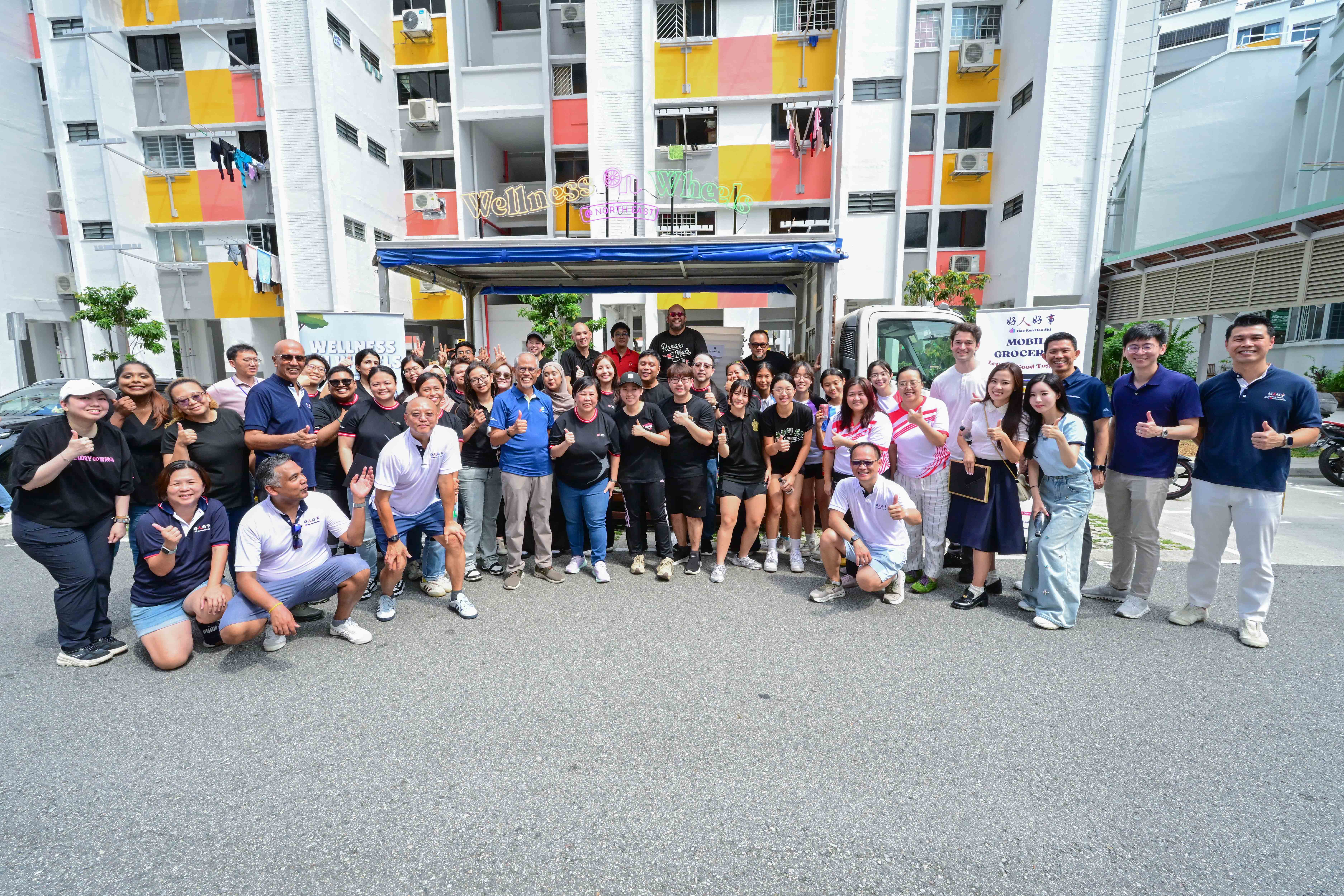 People posing for a photo in front of a wellness truck parked near a HDB building.