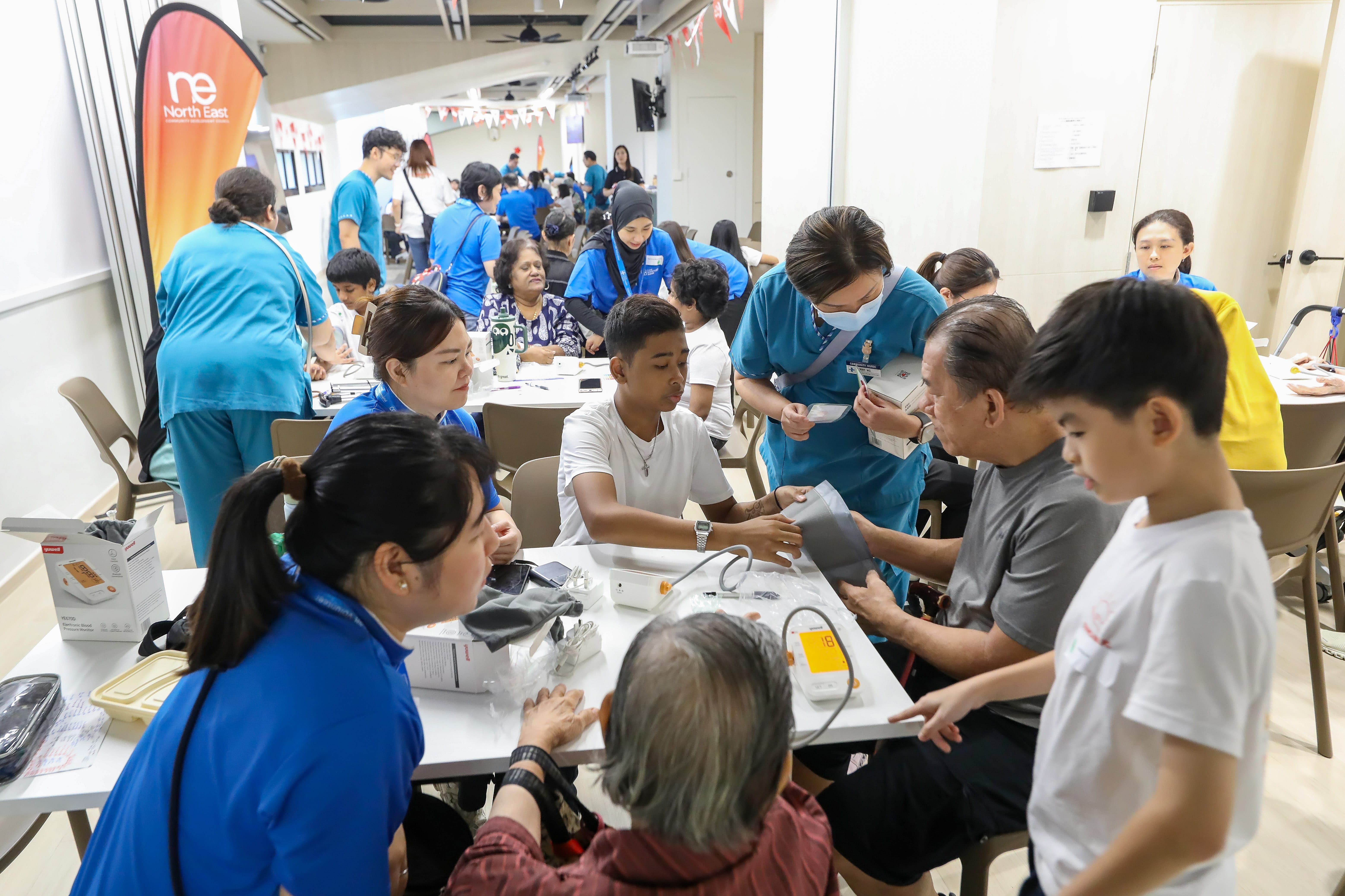 Young Health Hero practicing how to measure a senior's blood pressure, with guidance from a healthcare professionals during the programme's second day.